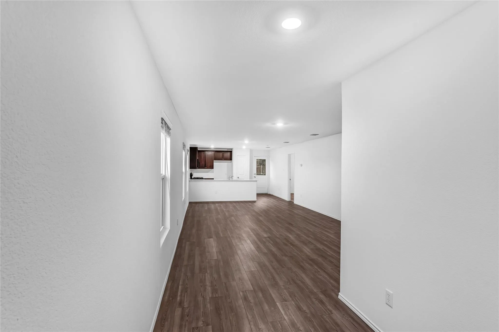 Corridor with dark wood-style floors and recessed lighting