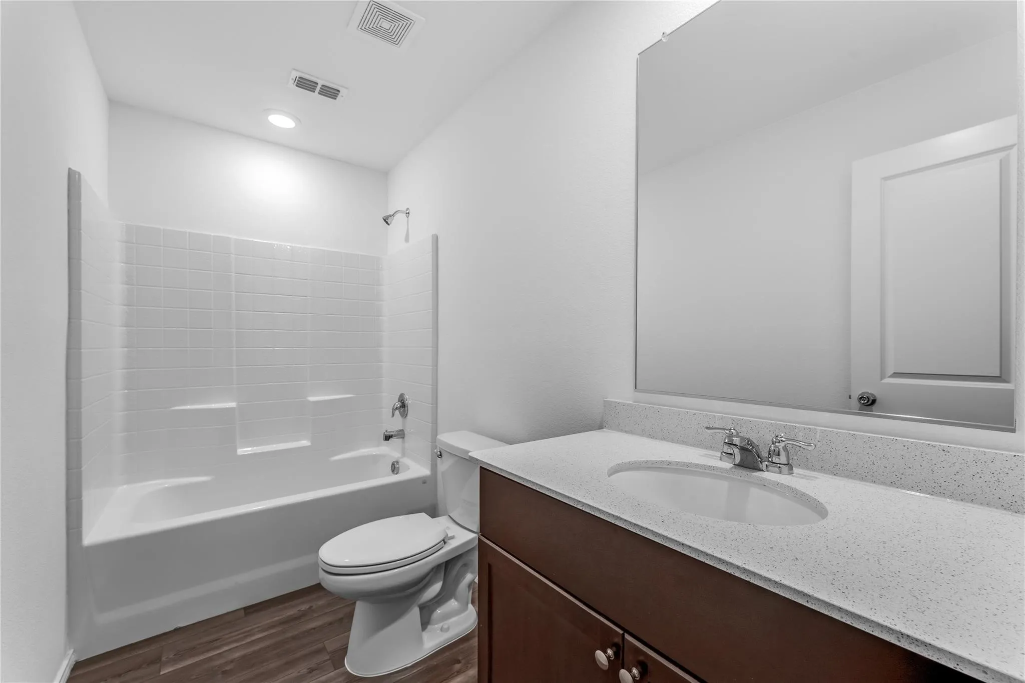 Full bathroom with shower / bath combination, vanity, and dark wood-type flooring