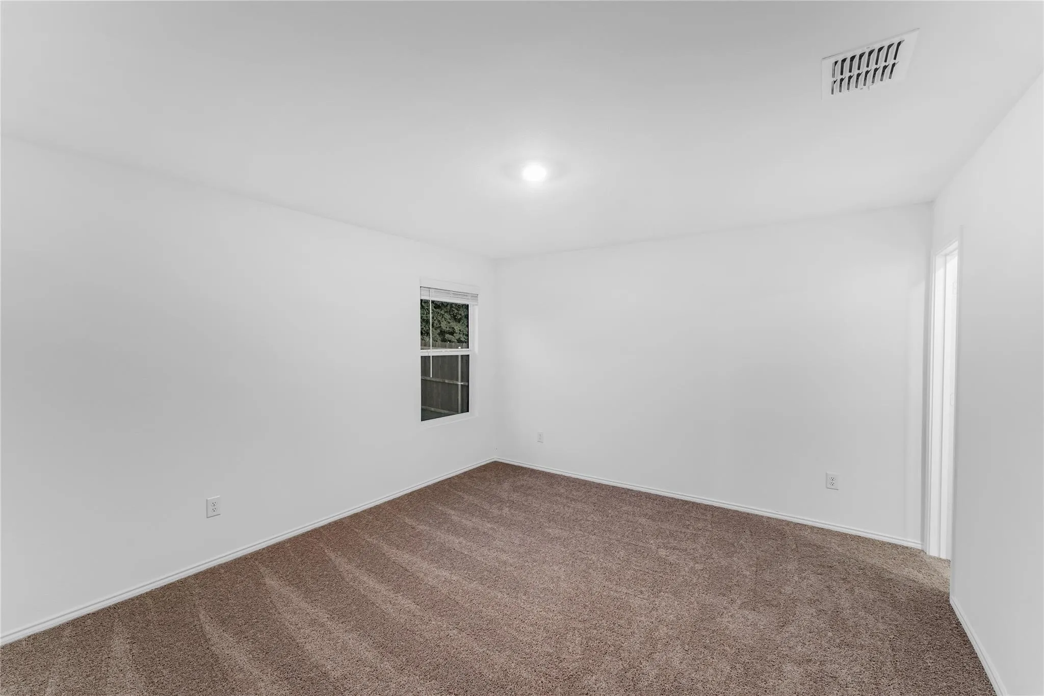 Carpeted spare room featuring baseboards