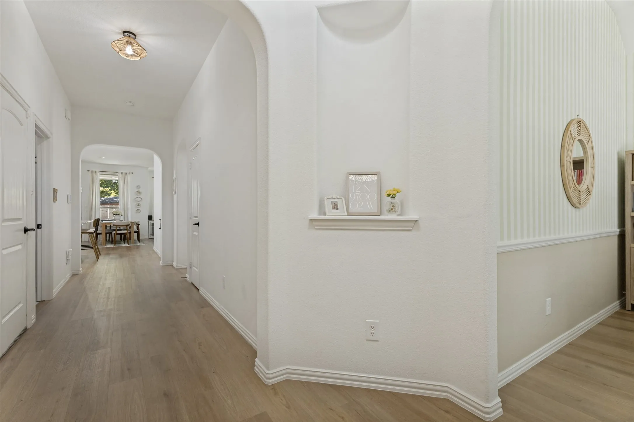 Hallway featuring wood-finish flooring, an arched doorway, and a built-in wall niche
