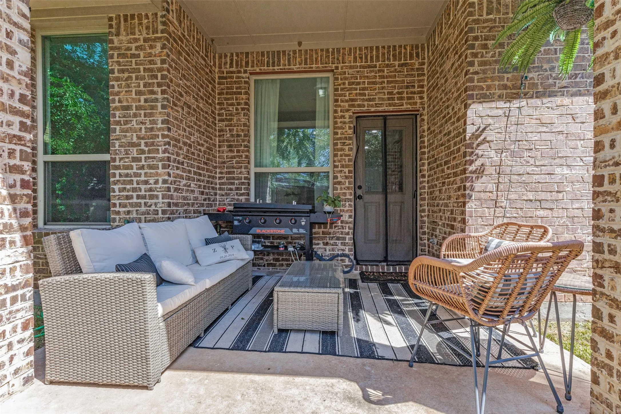 Covered patio featuring brick exterior walls, concrete flooring, and multiple windows