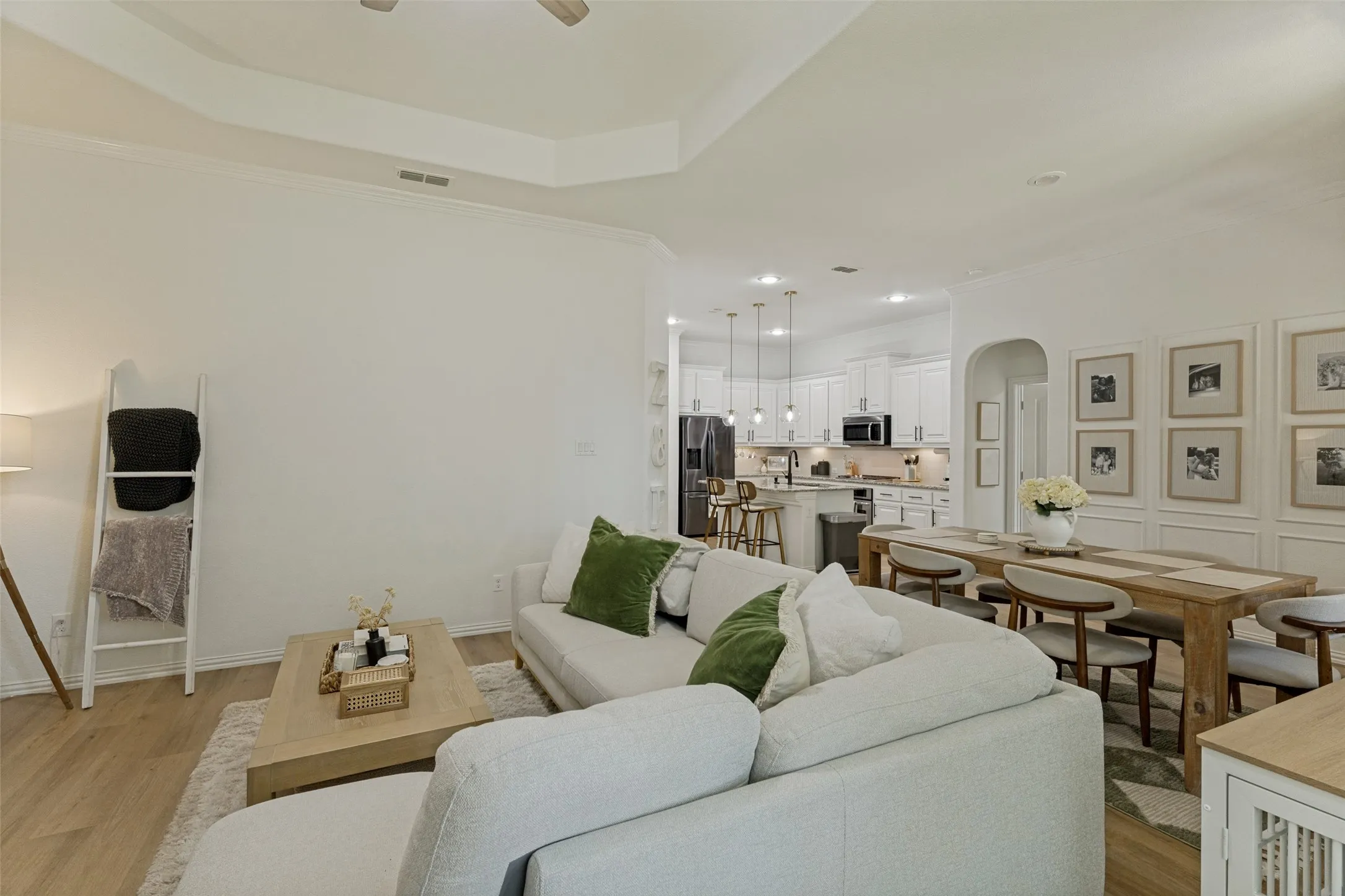 Open-concept living area with wood-finish flooring, a tray ceiling, and crown molding