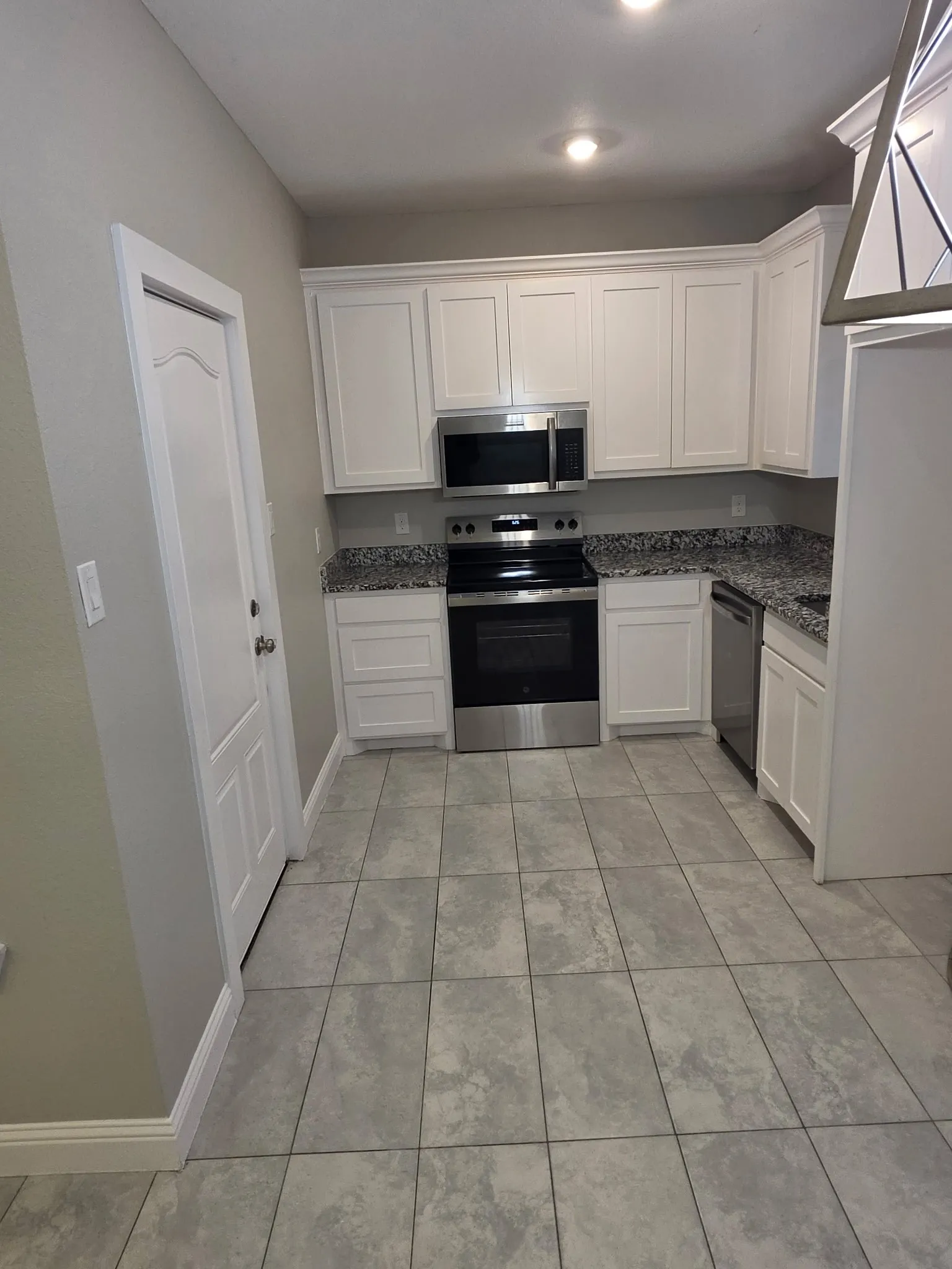 Kitchen featuring white cabinetry, granite countertops, stainless steel appliances, and tile flooring