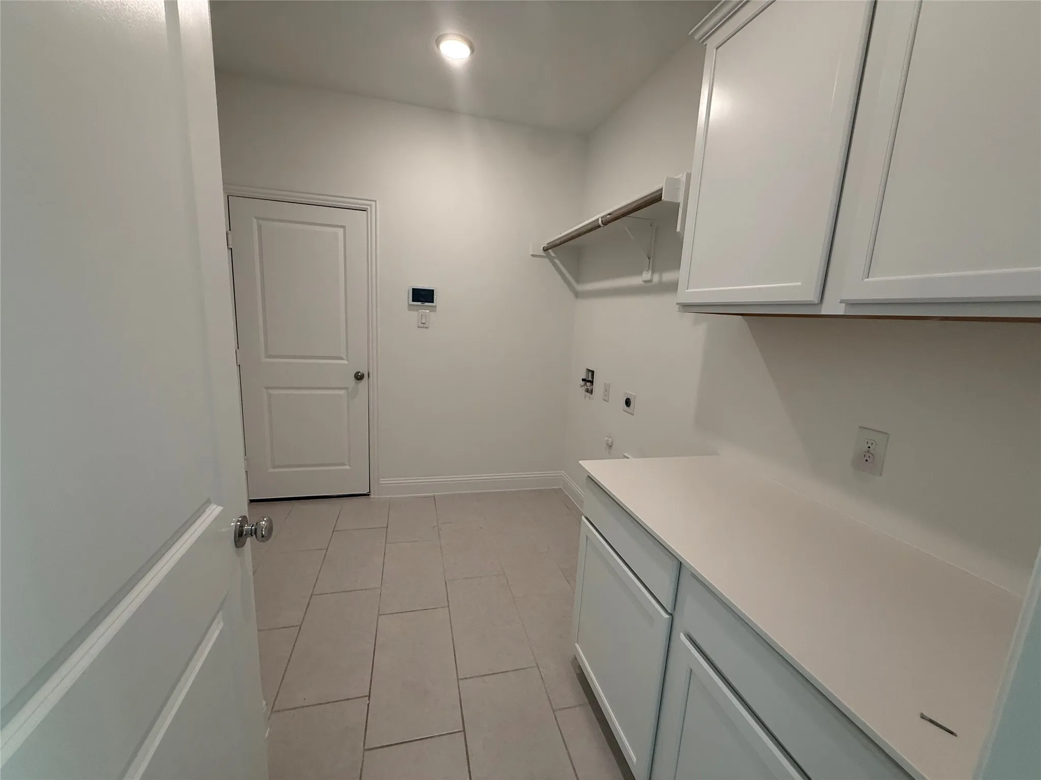 White shaker-style cabinetry with a smooth countertop, light-toned tile flooring, and integrated overhead lighting