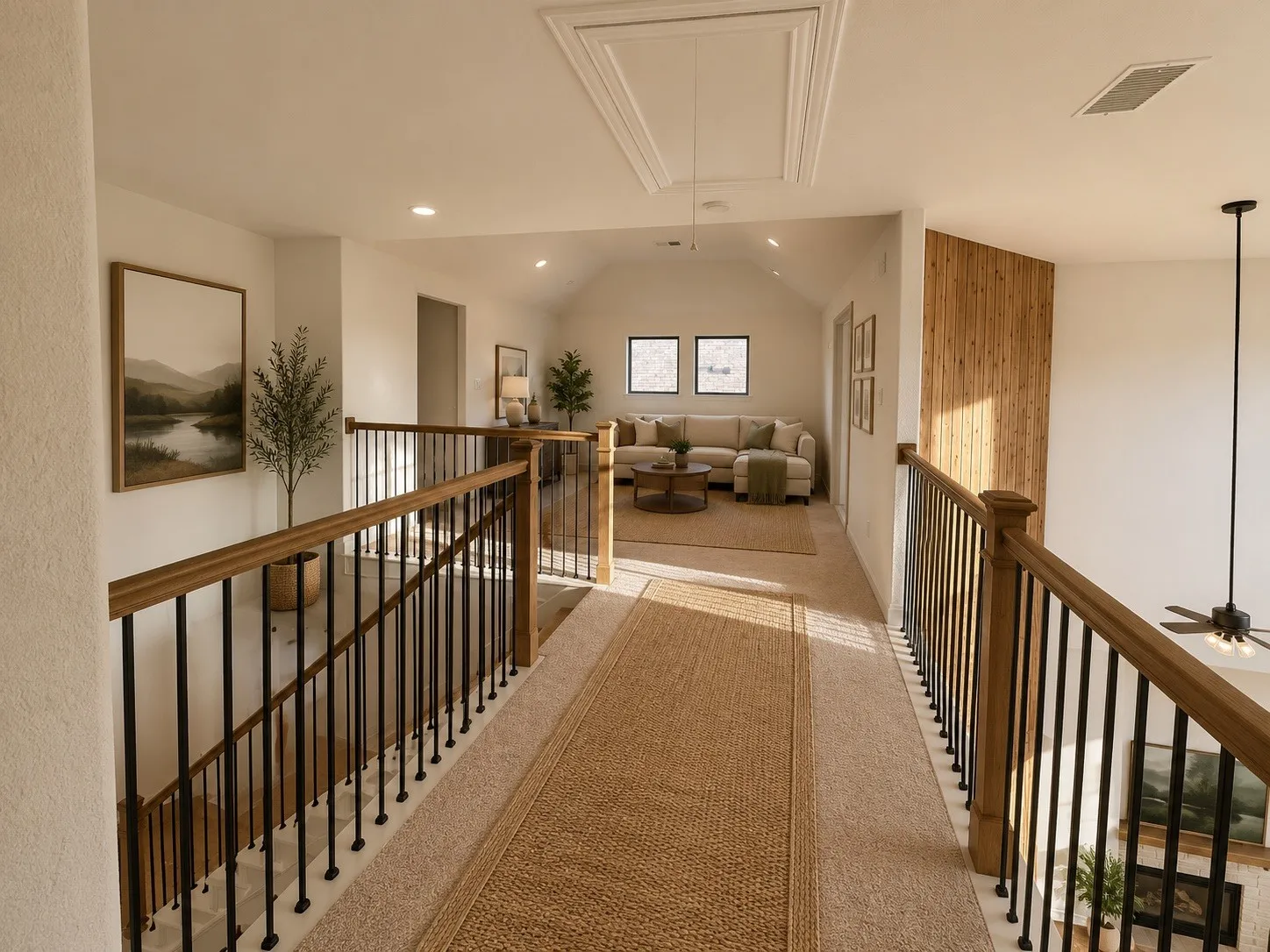 Open hallway with wood and metal railings, leading to a carpeted bonus room featuring a vaulted ceiling and recessed lighting