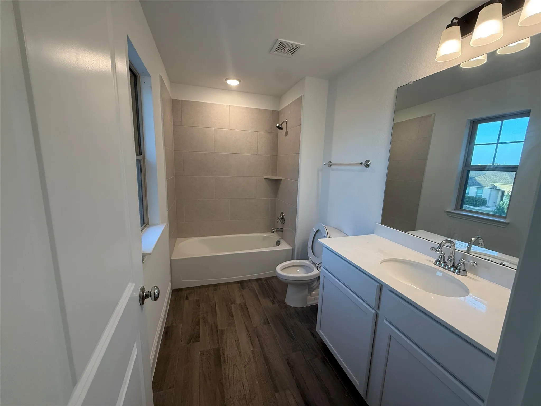 Bathroom featuring a white vanity with an undermount sink, a white countertop, and wood-finish flooring
