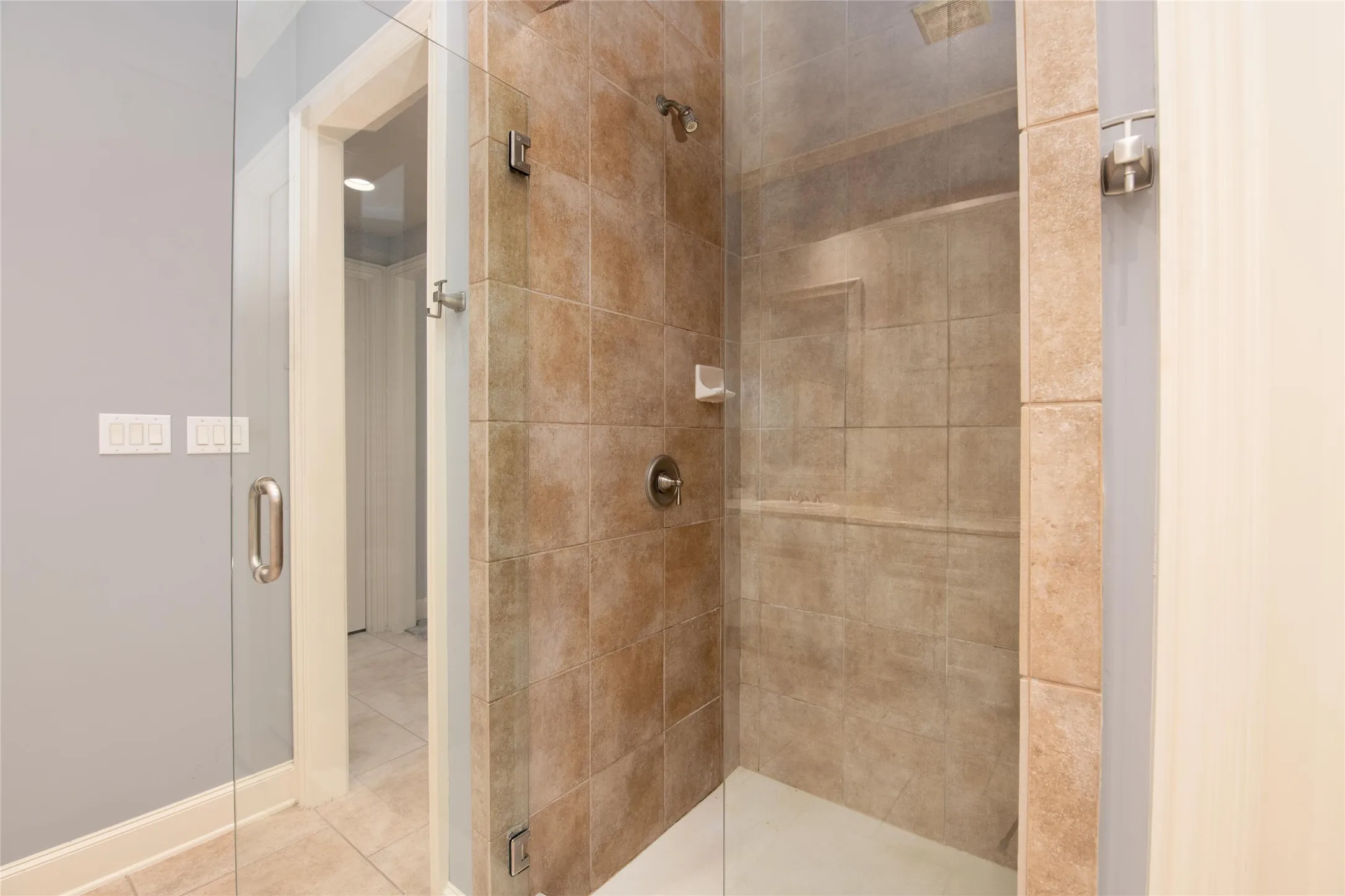 The beautifully tiled walk-in shower adds another luxurious element to the well-appointed primary bath.