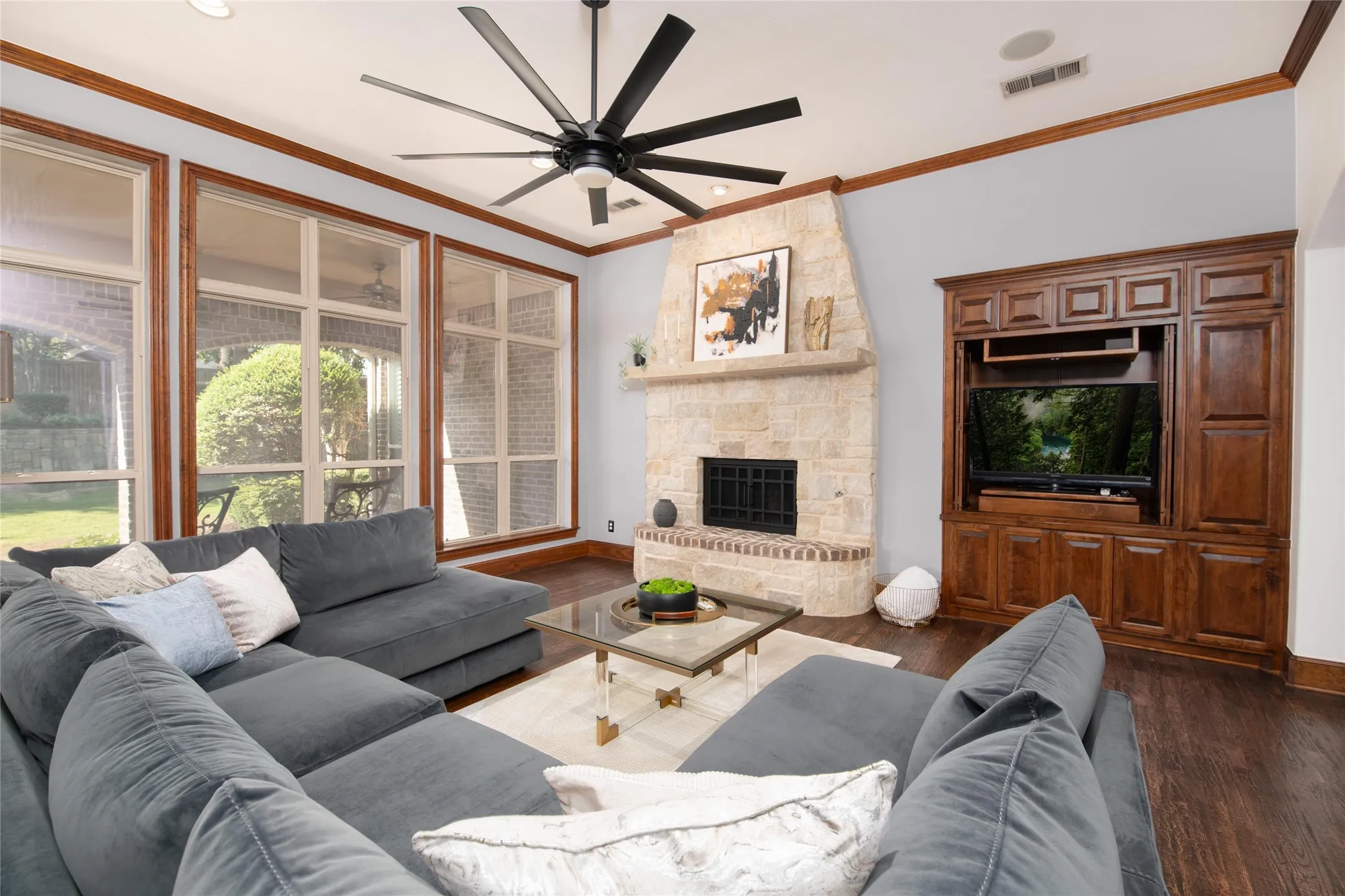 The light-filled living room showcases a dramatic fireplace, custom woodwork and expansive windows overlooking the backyard.
