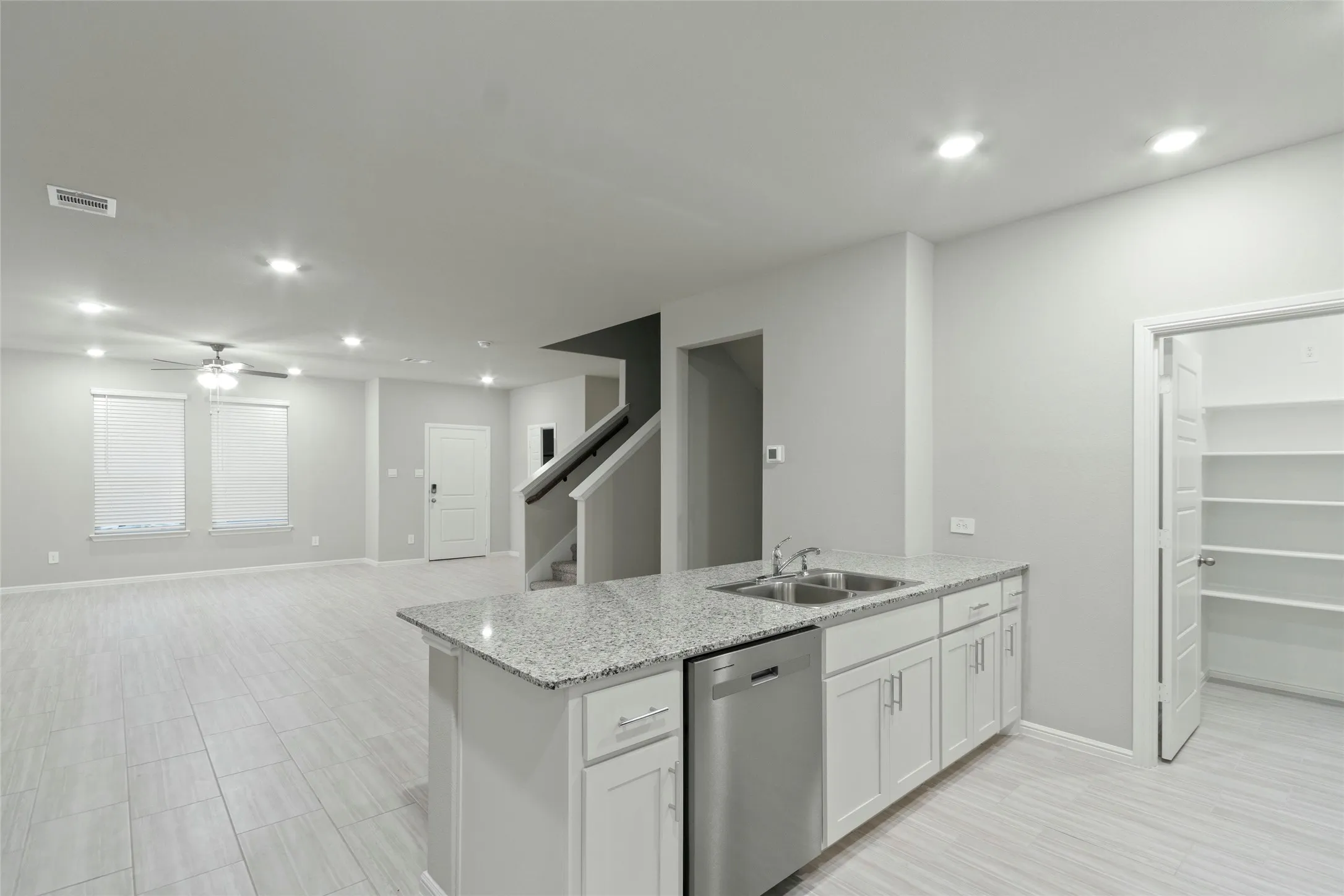 Kitchen featuring visible vents, dishwasher, a sink, a peninsula, and white cabinetry