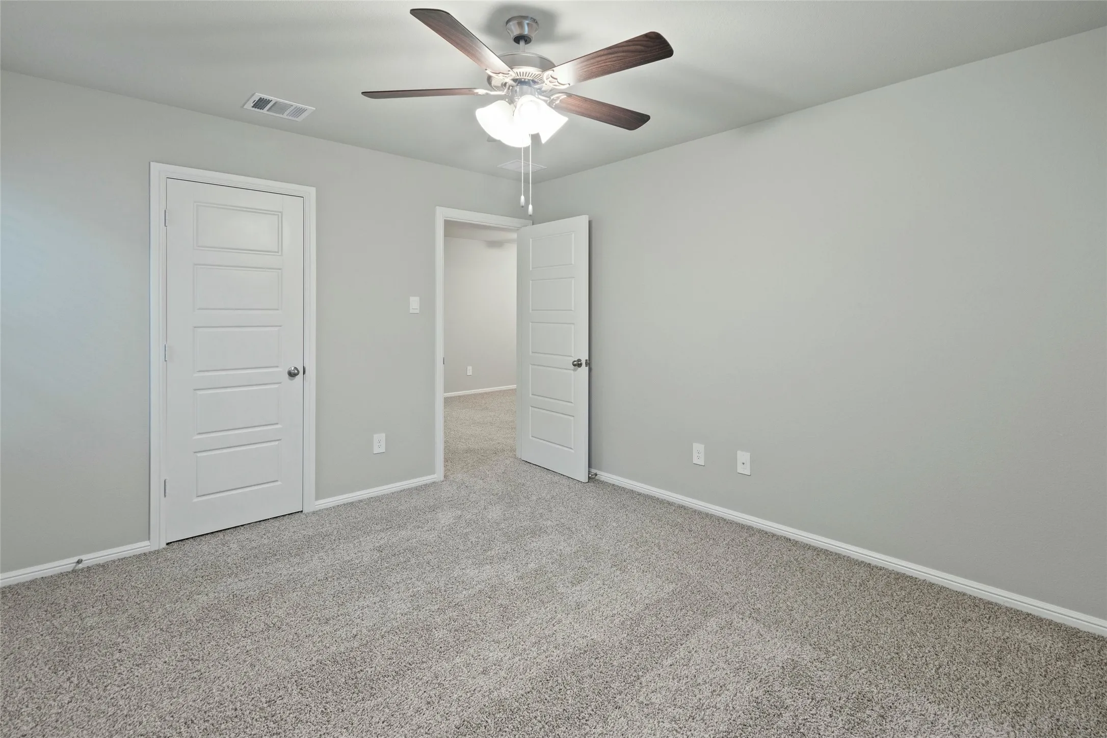 Unfurnished bedroom with carpet flooring, visible vents, baseboards, and ceiling fan