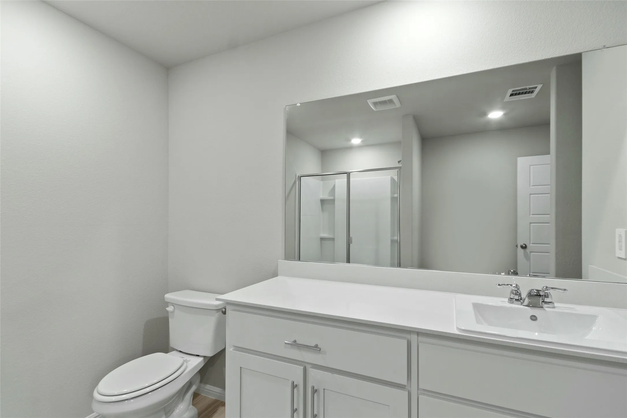 Full bathroom featuring a shower stall, vanity, visible vents, and toilet