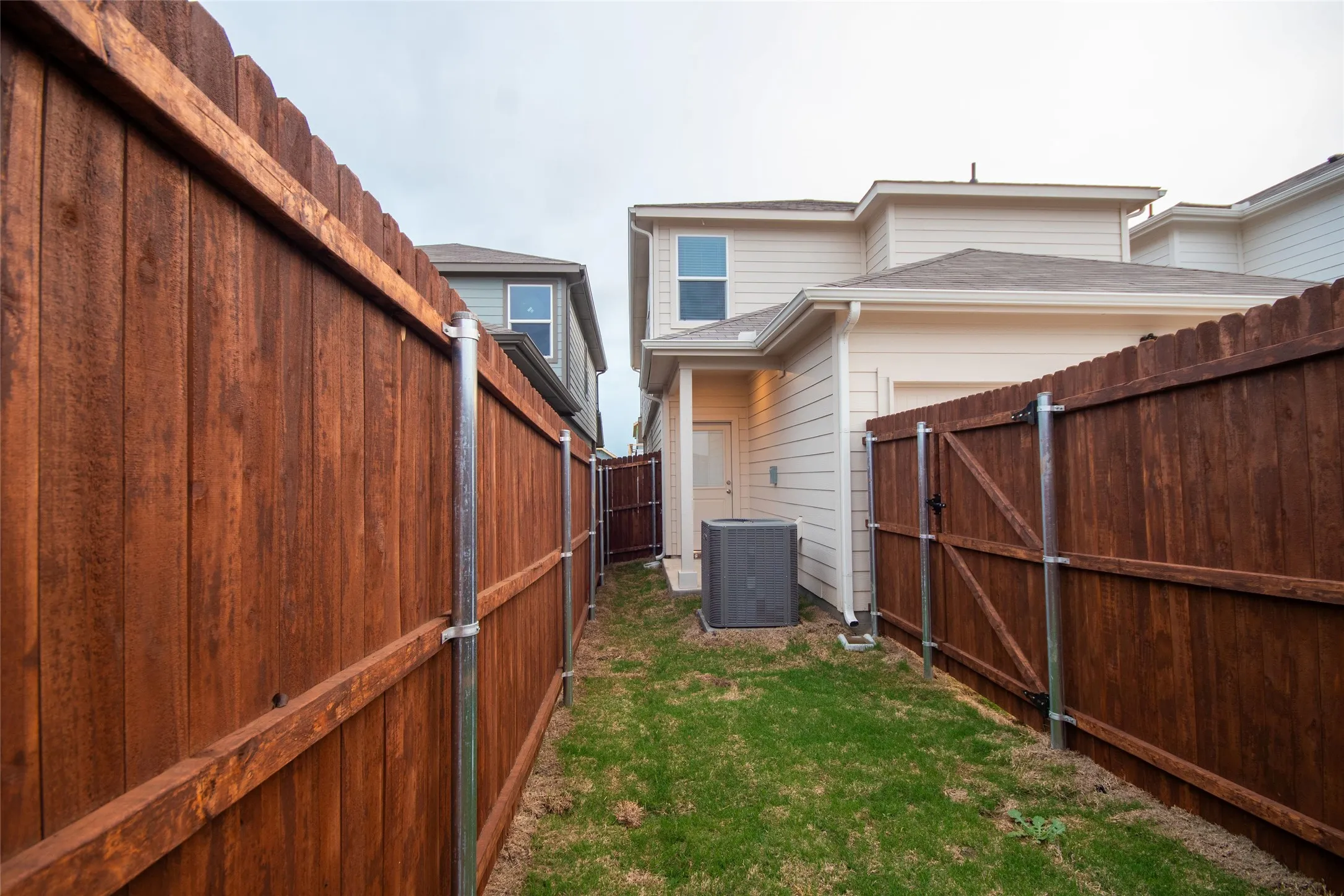 View of yard with cooling unit, a fenced backyard, and a gate