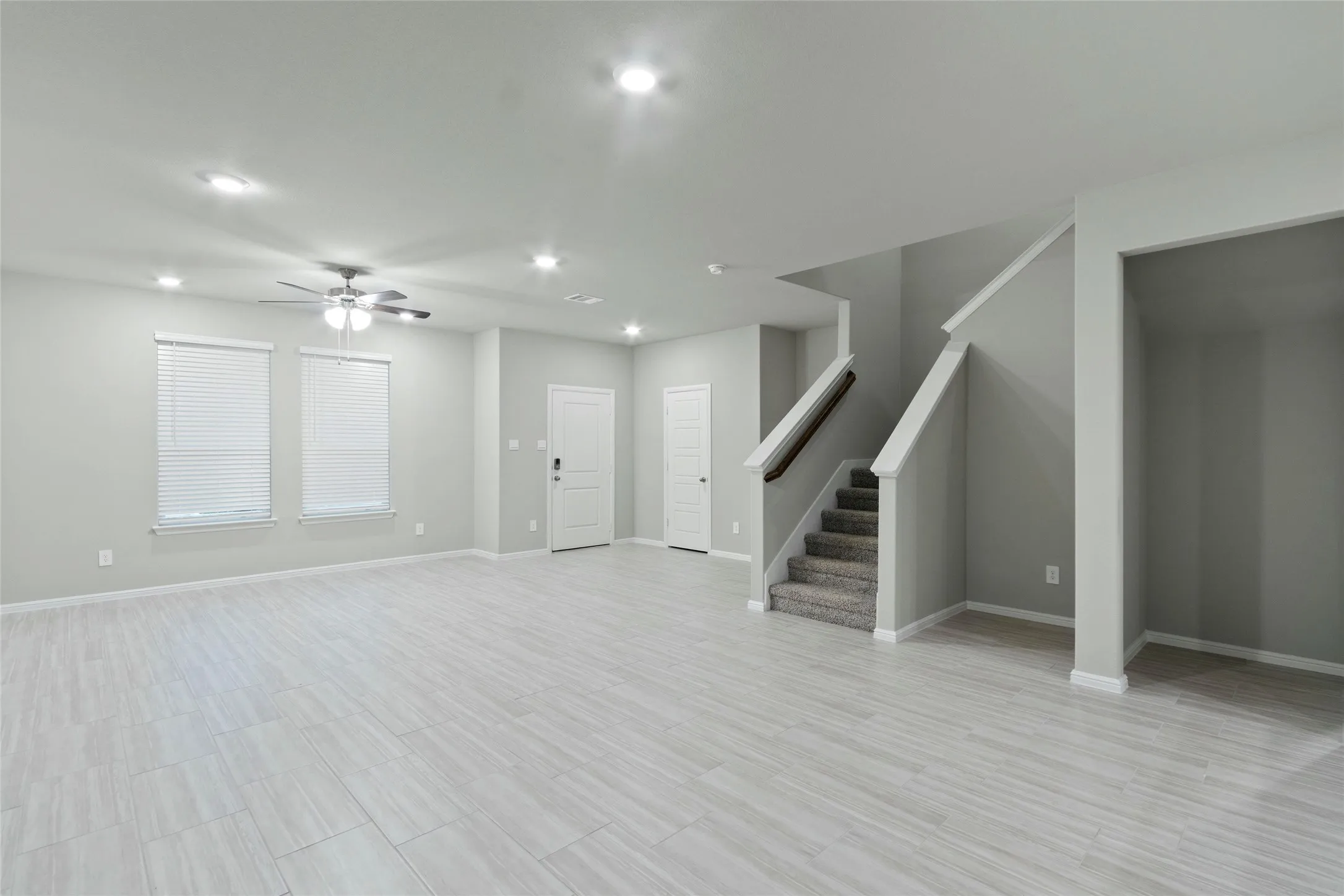 Unfurnished living room with recessed lighting, baseboards, a ceiling fan, and stairs