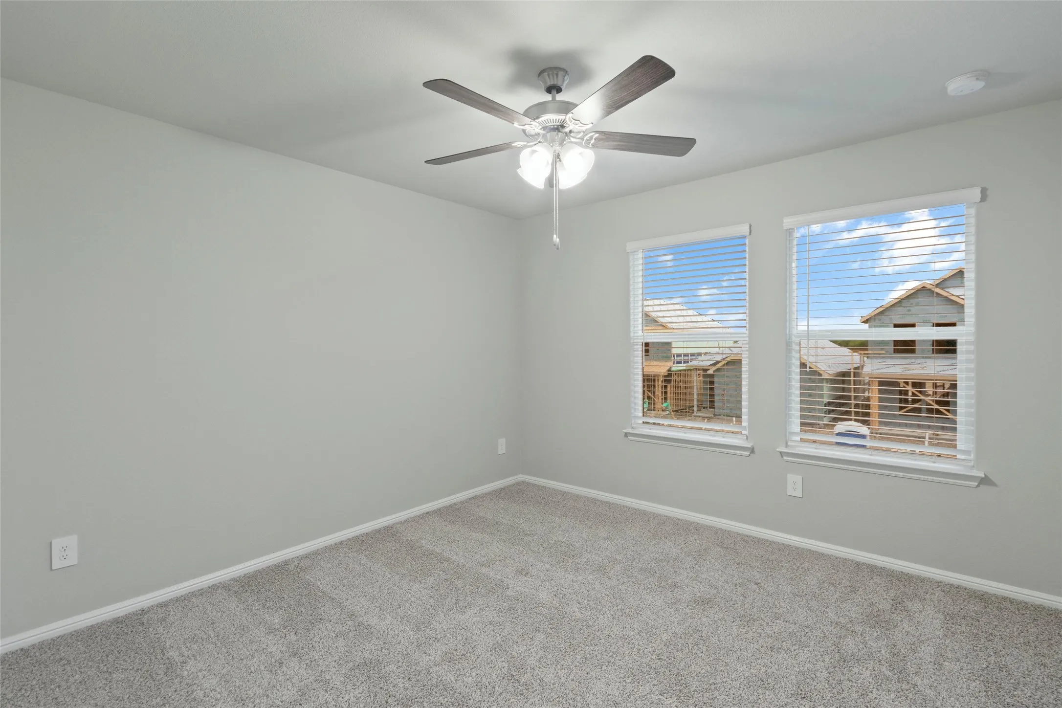Carpeted empty room with baseboards and a ceiling fan