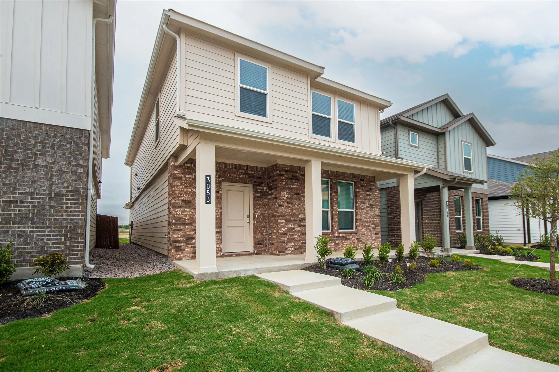 View of front facade featuring board and batten siding, a front lawn, and brick siding