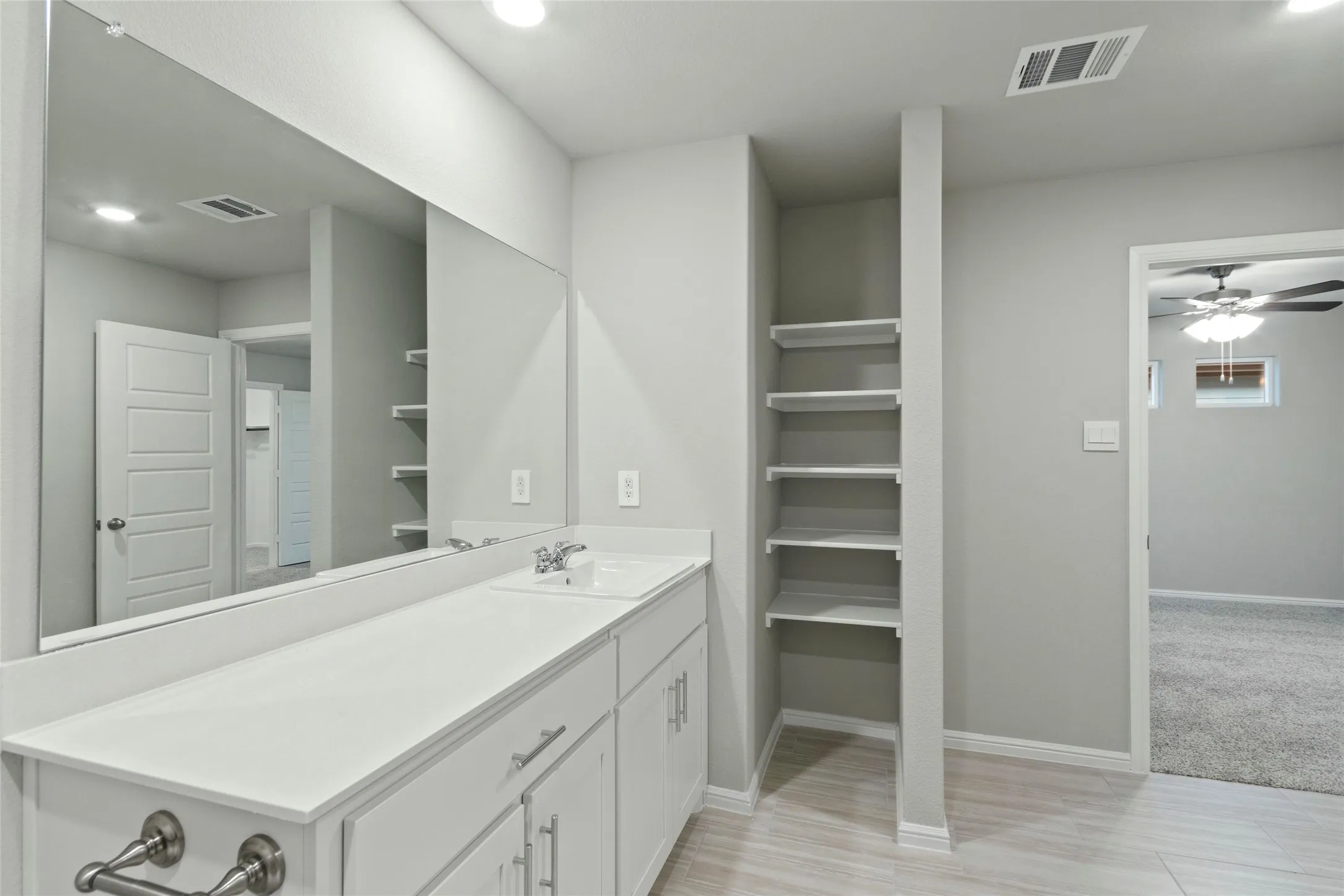 Bathroom featuring visible vents, ceiling fan, vanity, and baseboards
