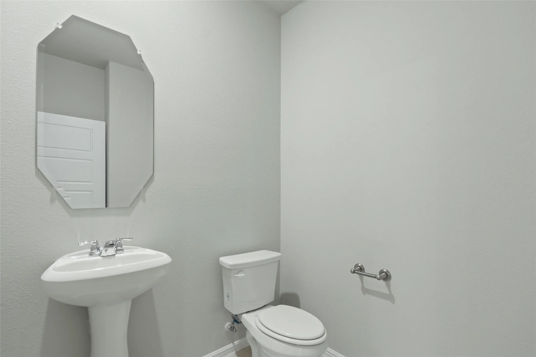 Half bath with toilet, a sink, and baseboards