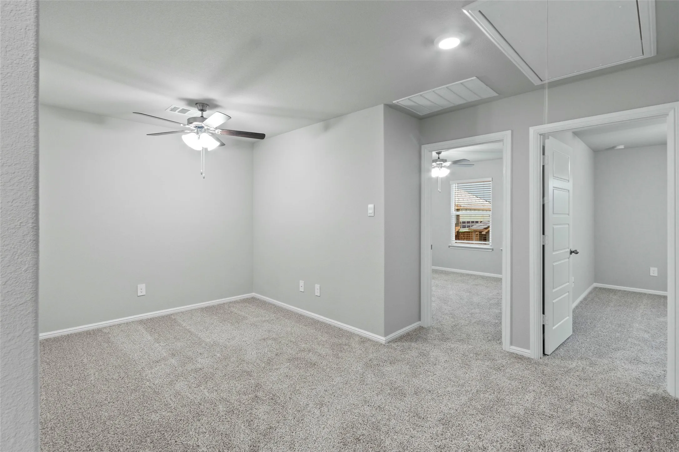 Unfurnished room with carpet flooring, baseboards, a ceiling fan, and attic access