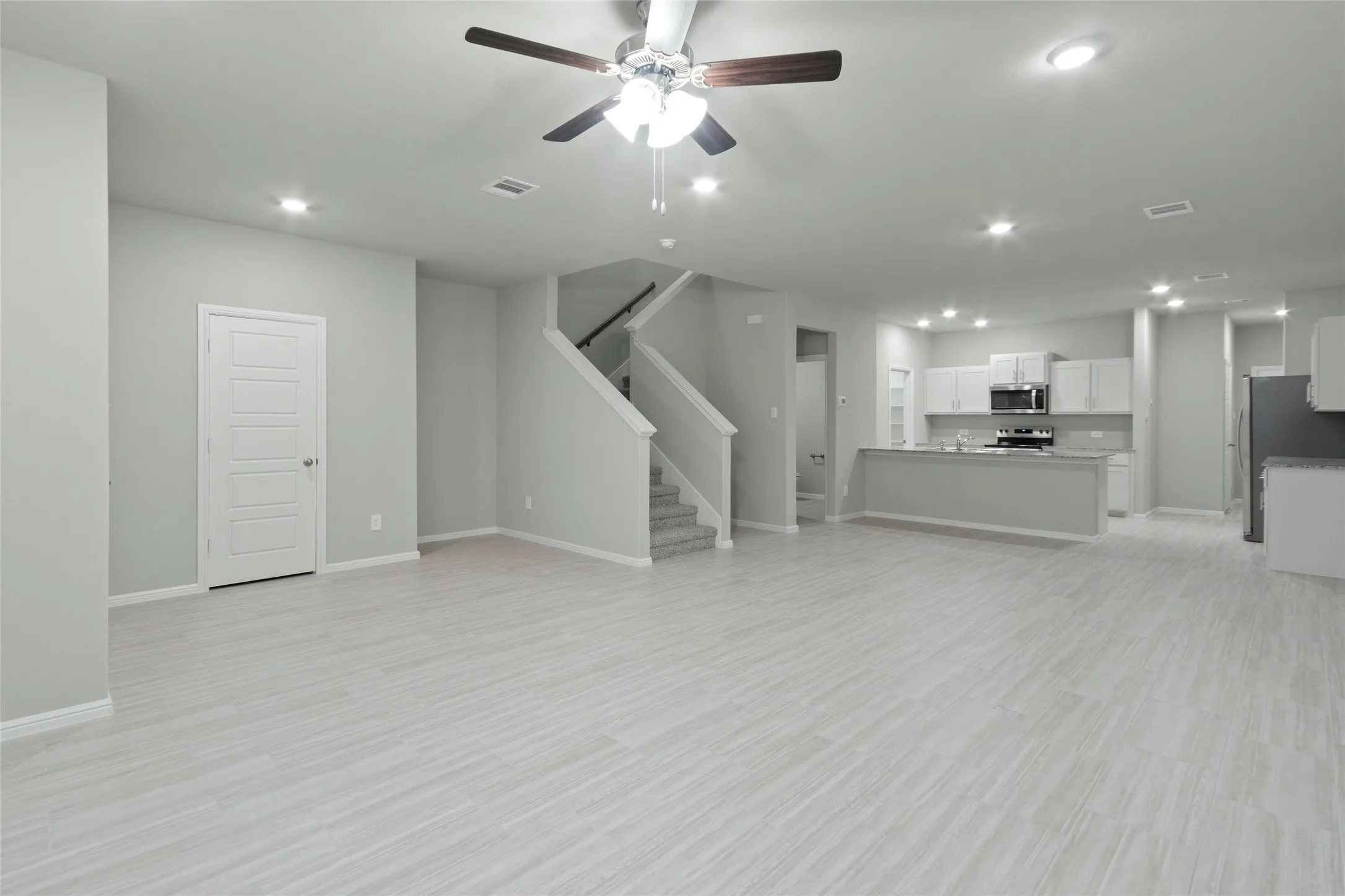 Unfurnished living room featuring stairway, visible vents, baseboards, and ceiling fan