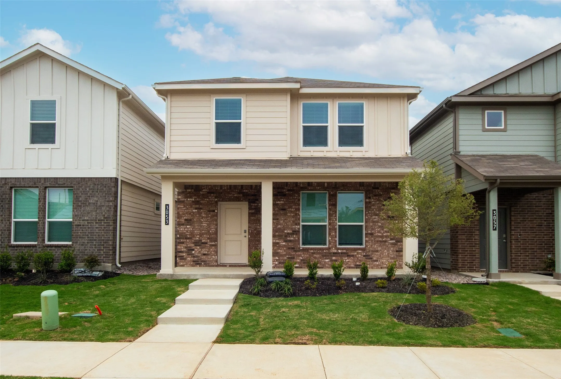 View of front facade featuring board and batten siding, a front yard, and brick siding