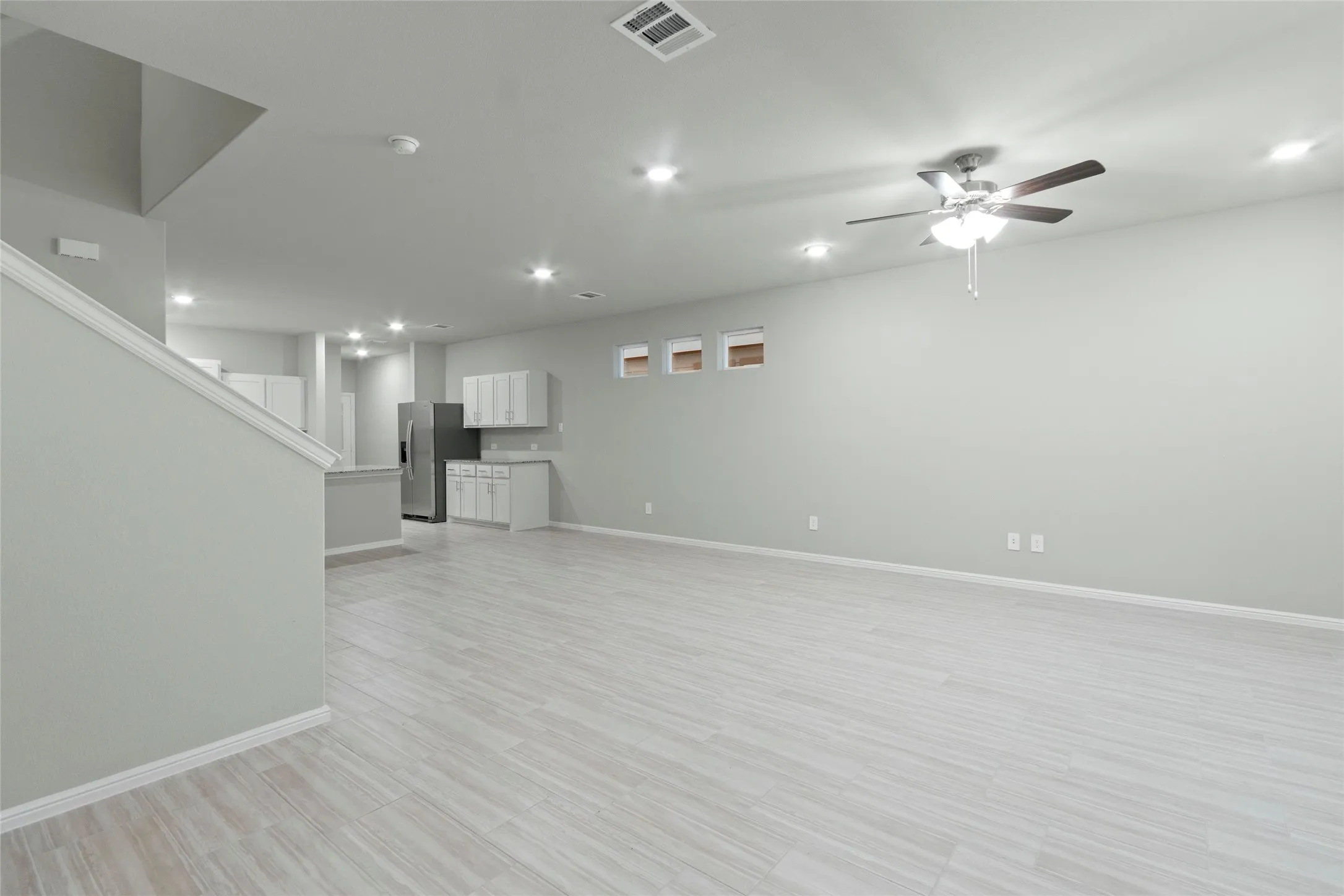 Unfurnished living room with baseboards, a ceiling fan, visible vents, and recessed lighting