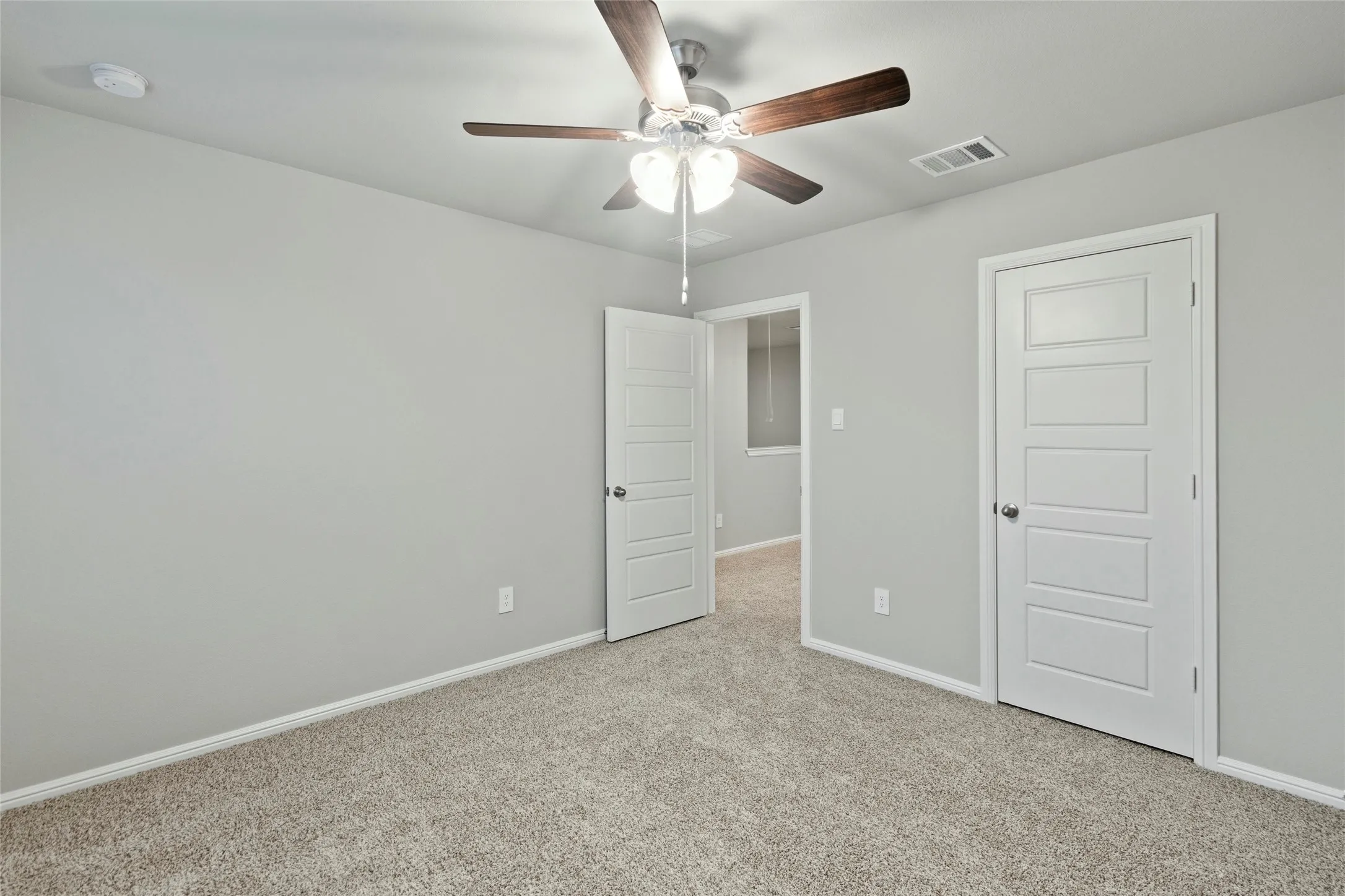 Unfurnished bedroom featuring carpet flooring, baseboards, a ceiling fan, and visible vents