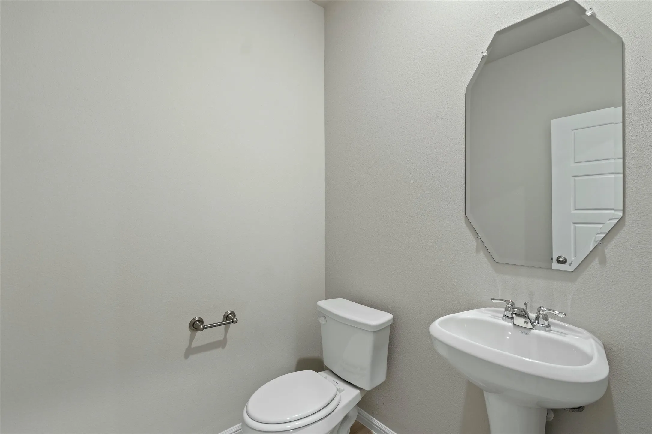 Half bathroom featuring a sink, toilet, and baseboards