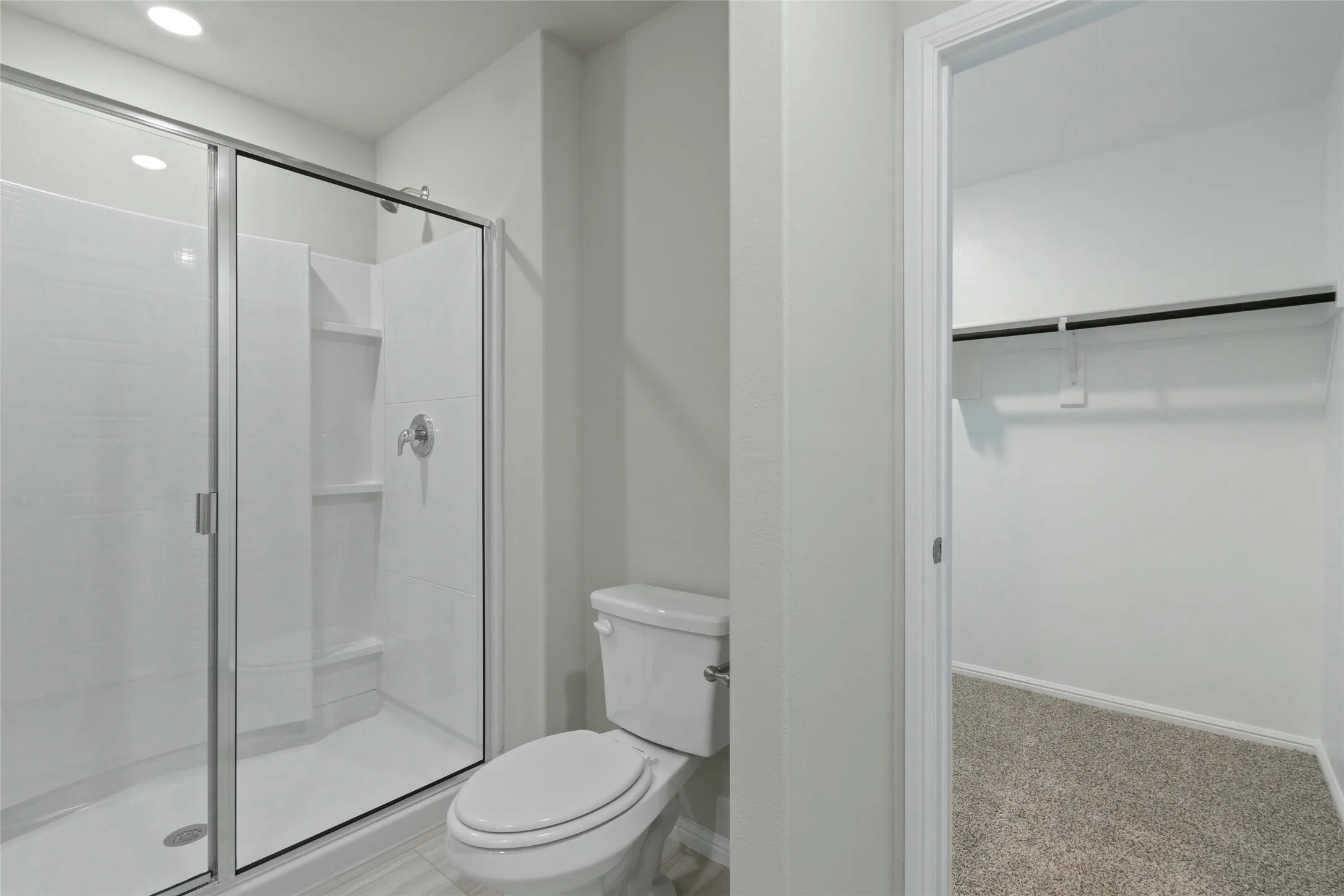 Bathroom with toilet, baseboards, recessed lighting, and a stall shower