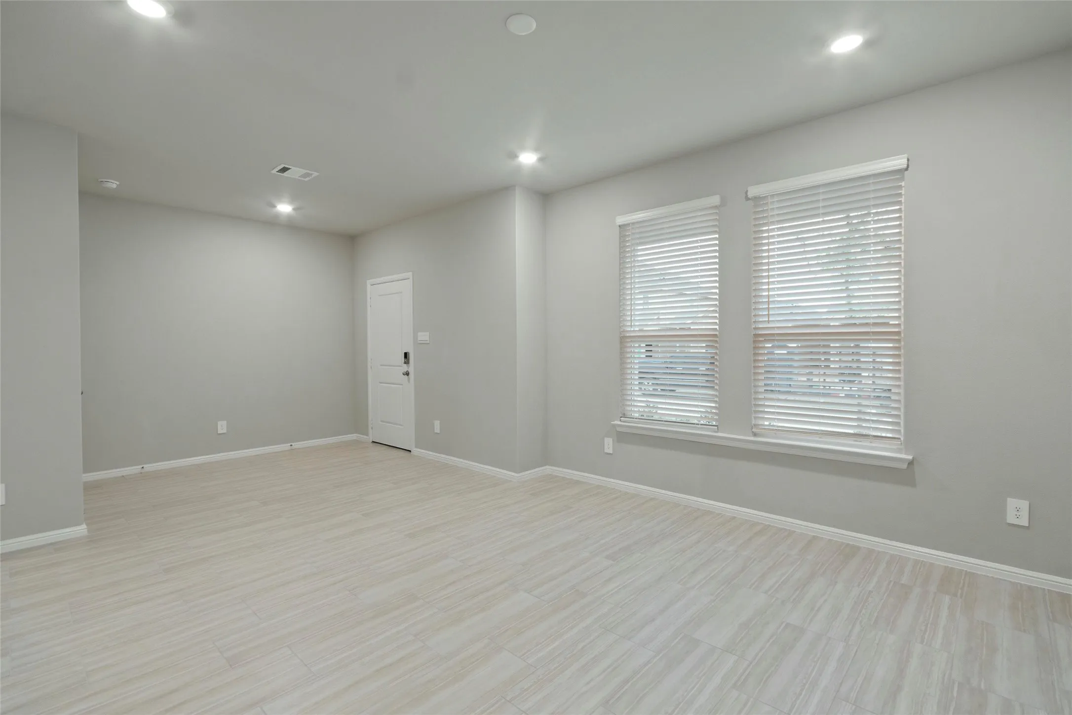 Living room featuring visible vents, baseboards, recessed lighting, and light wood-style floors