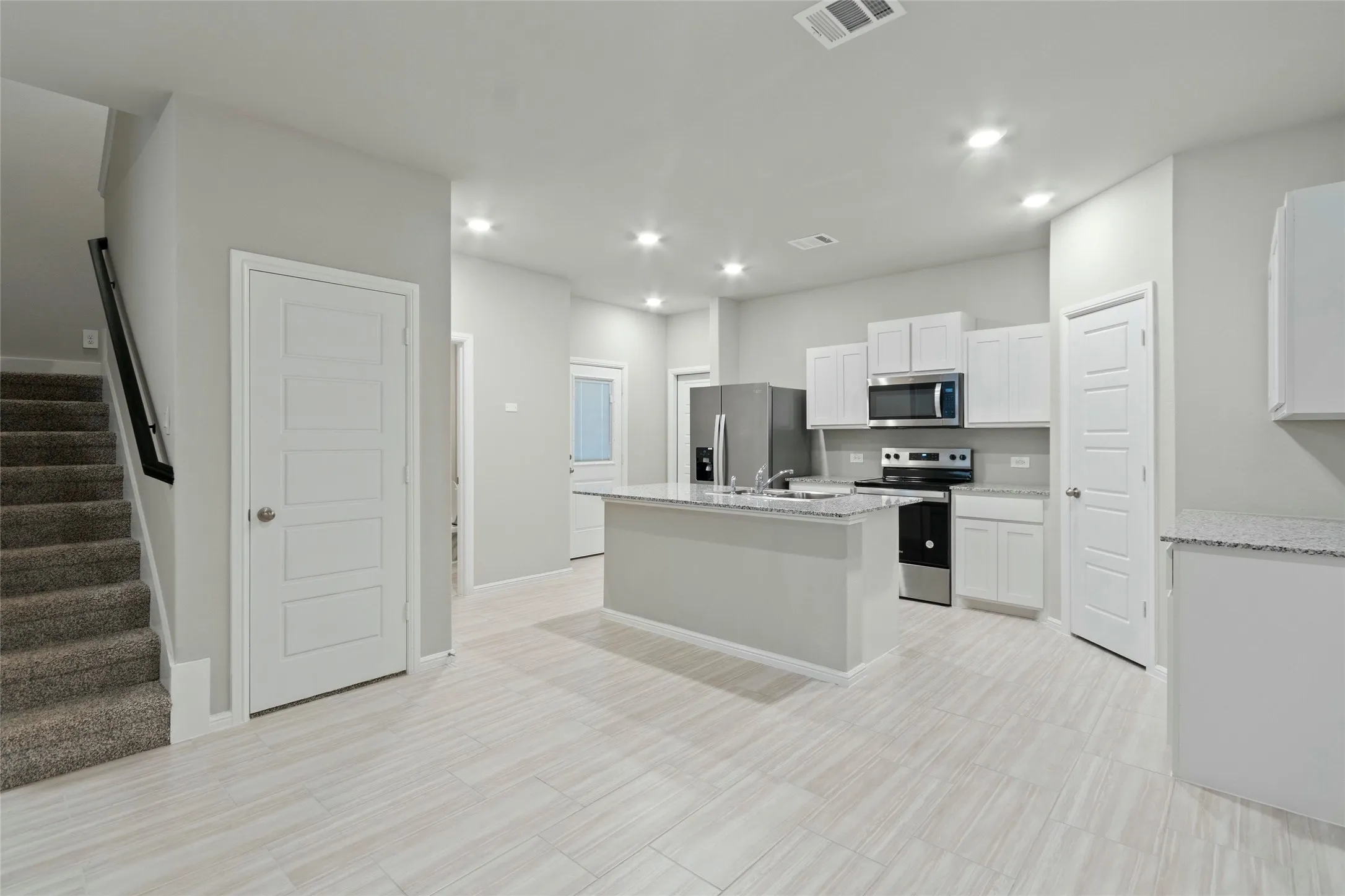 Kitchen featuring visible vents, appliances with stainless steel finishes, an island with sink, white cabinetry, and recessed lighting