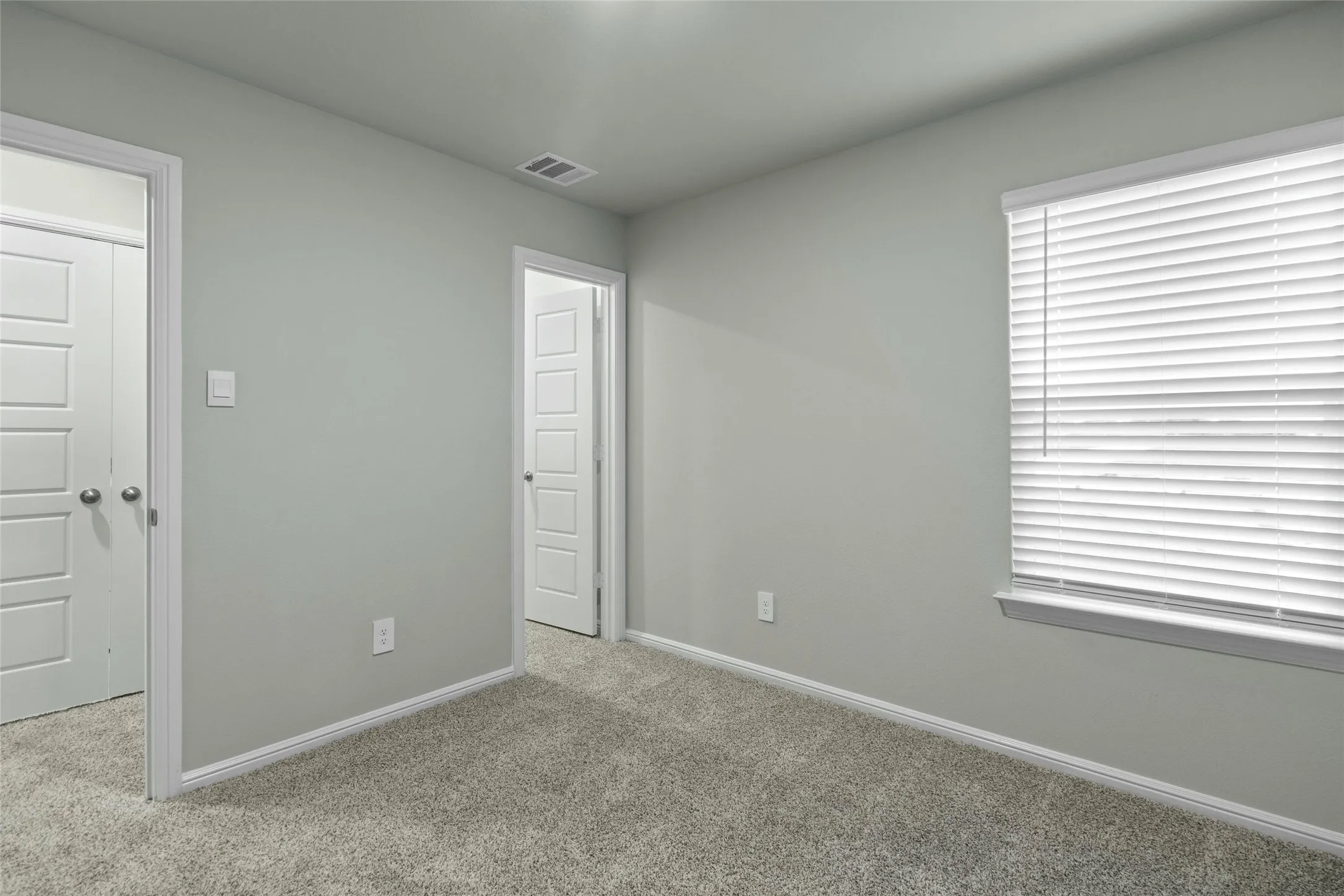Unfurnished bedroom with baseboards, carpet, and visible vents