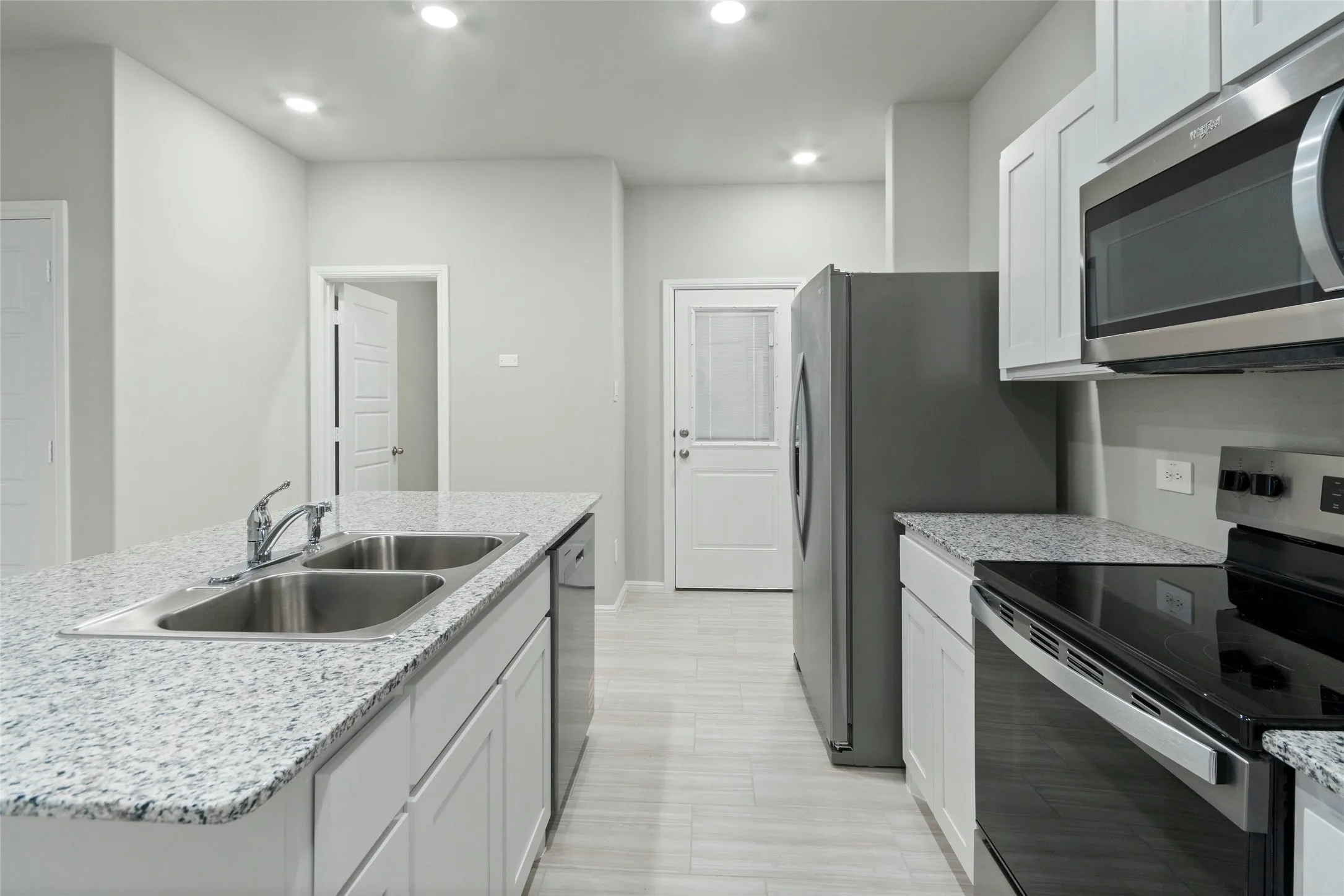 Kitchen with baseboards, recessed lighting, white cabinetry, appliances with stainless steel finishes, and a sink