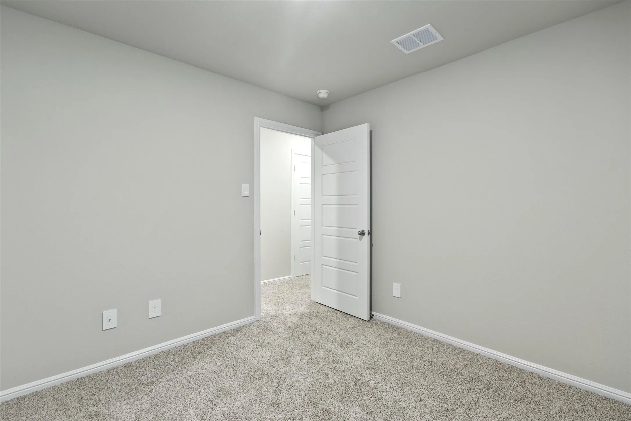 Unfurnished bedroom with visible vents, light colored carpet, and baseboards