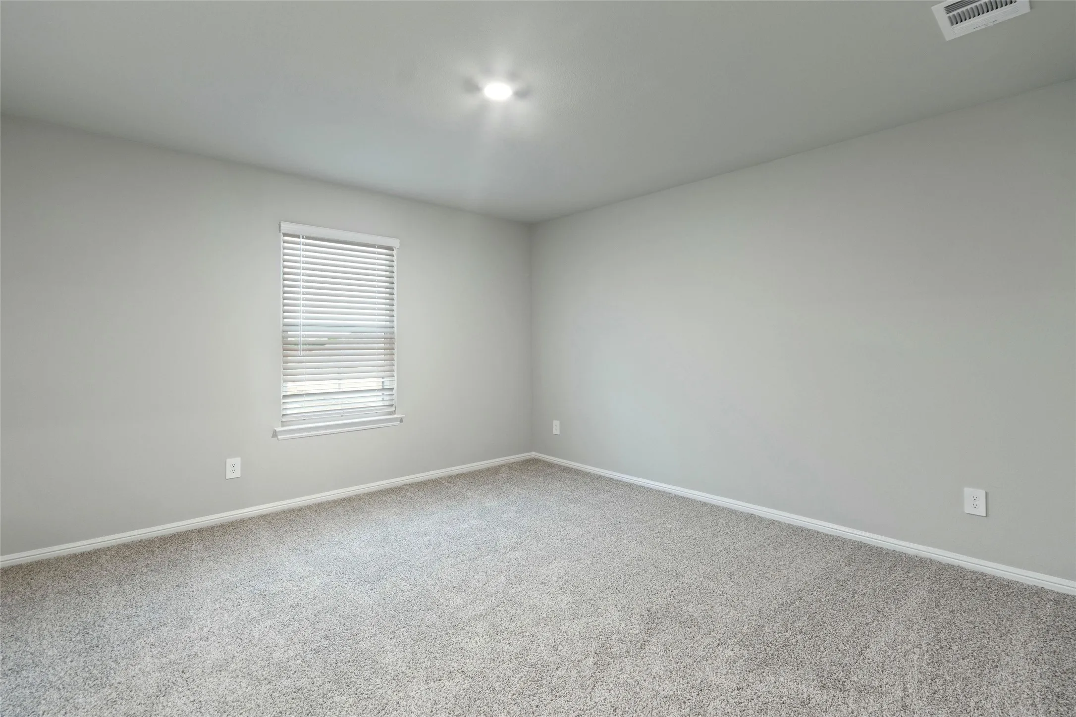 Carpeted empty room featuring visible vents and baseboards