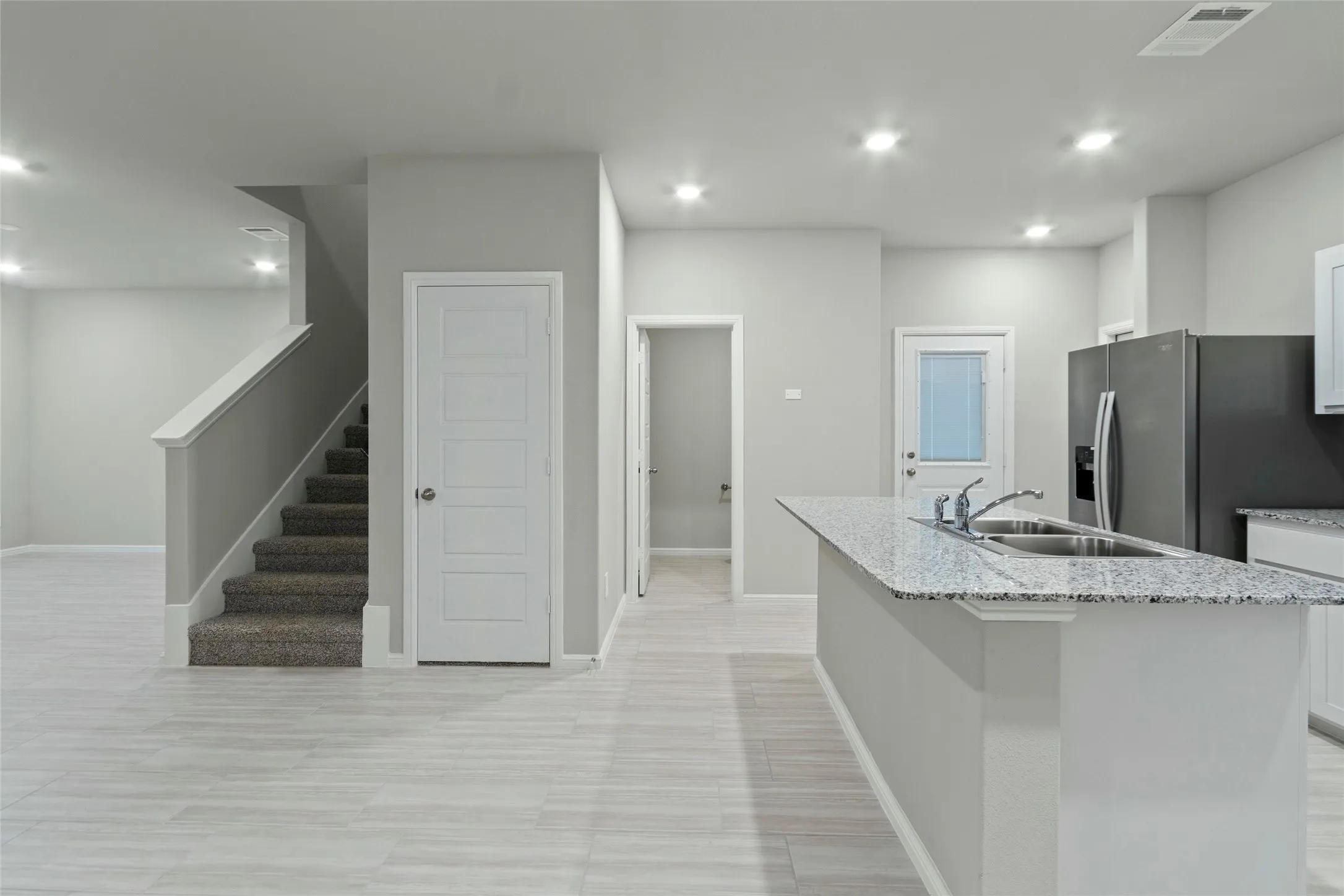 Kitchen with stainless steel fridge with ice dispenser, white cabinetry, visible vents, a kitchen island with sink, and a sink