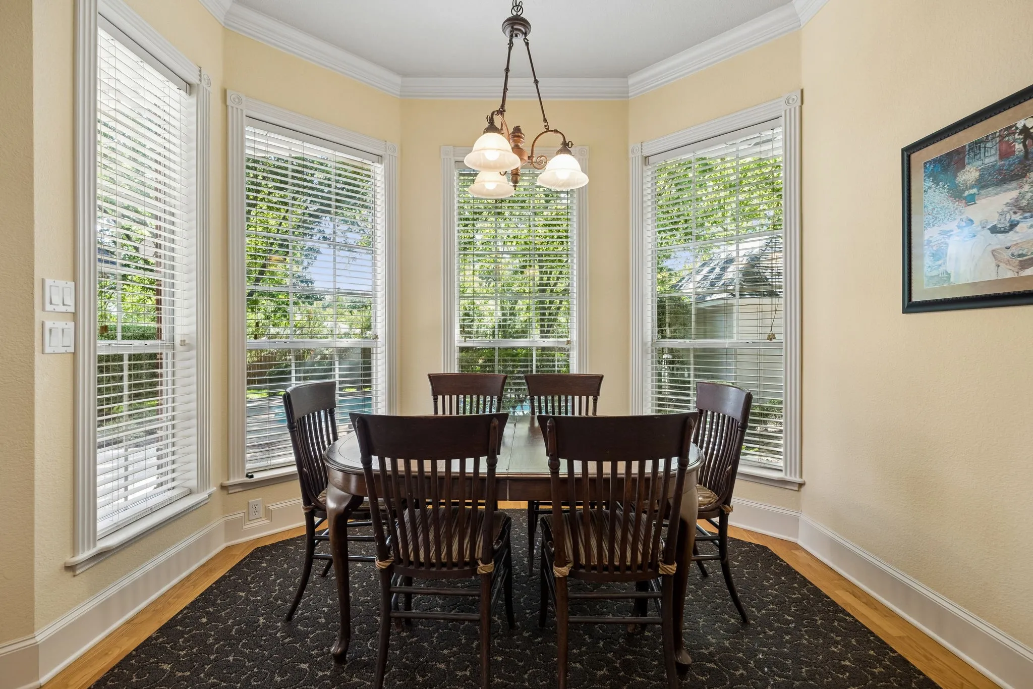 Bay window dining area featuring multiple windows overlooking the pool, crown molding, and wood flooring