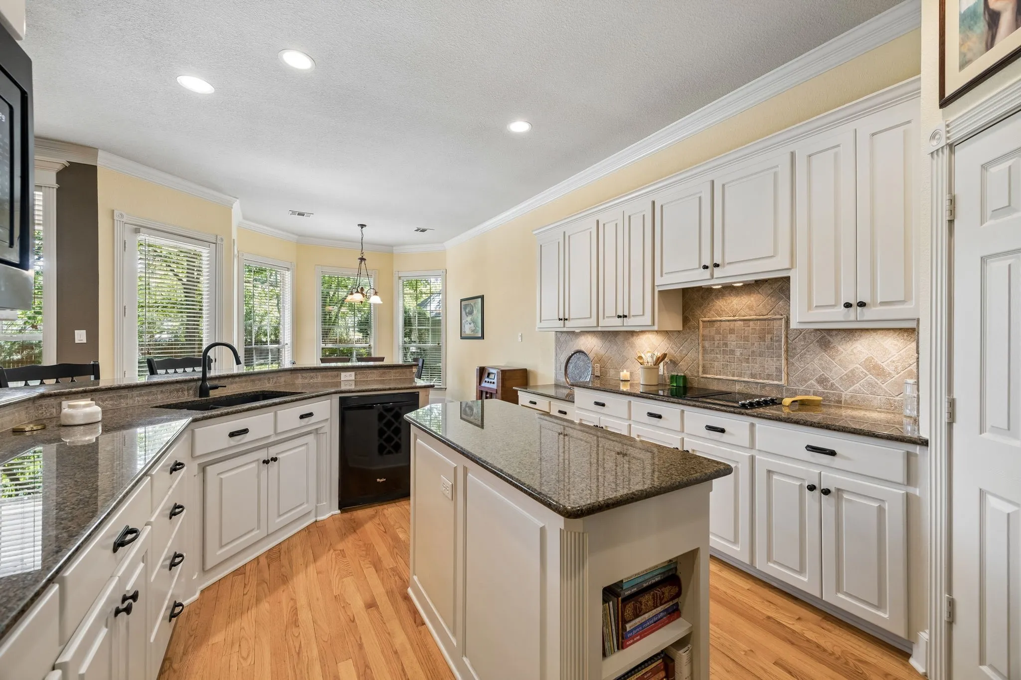 Kitchen featuring painted cabinetry, wood flooring, recessed lighting, and a kitchen island with built-in wine storage