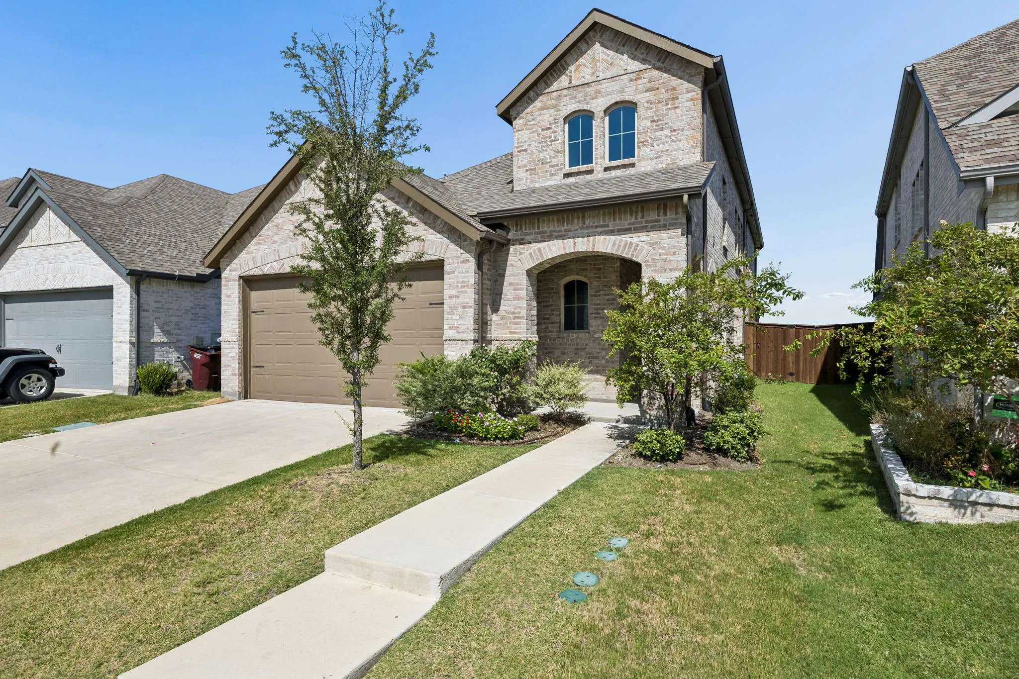 Brick exterior with an arched entry, two-car garage, and a concrete pathway