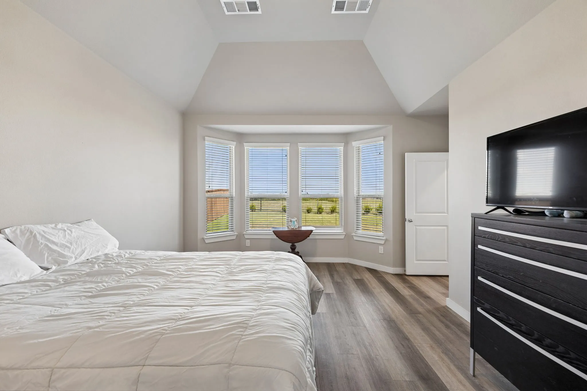 Tray ceiling, wood-finish flooring, bay window, white interior door, and neutral wall tones