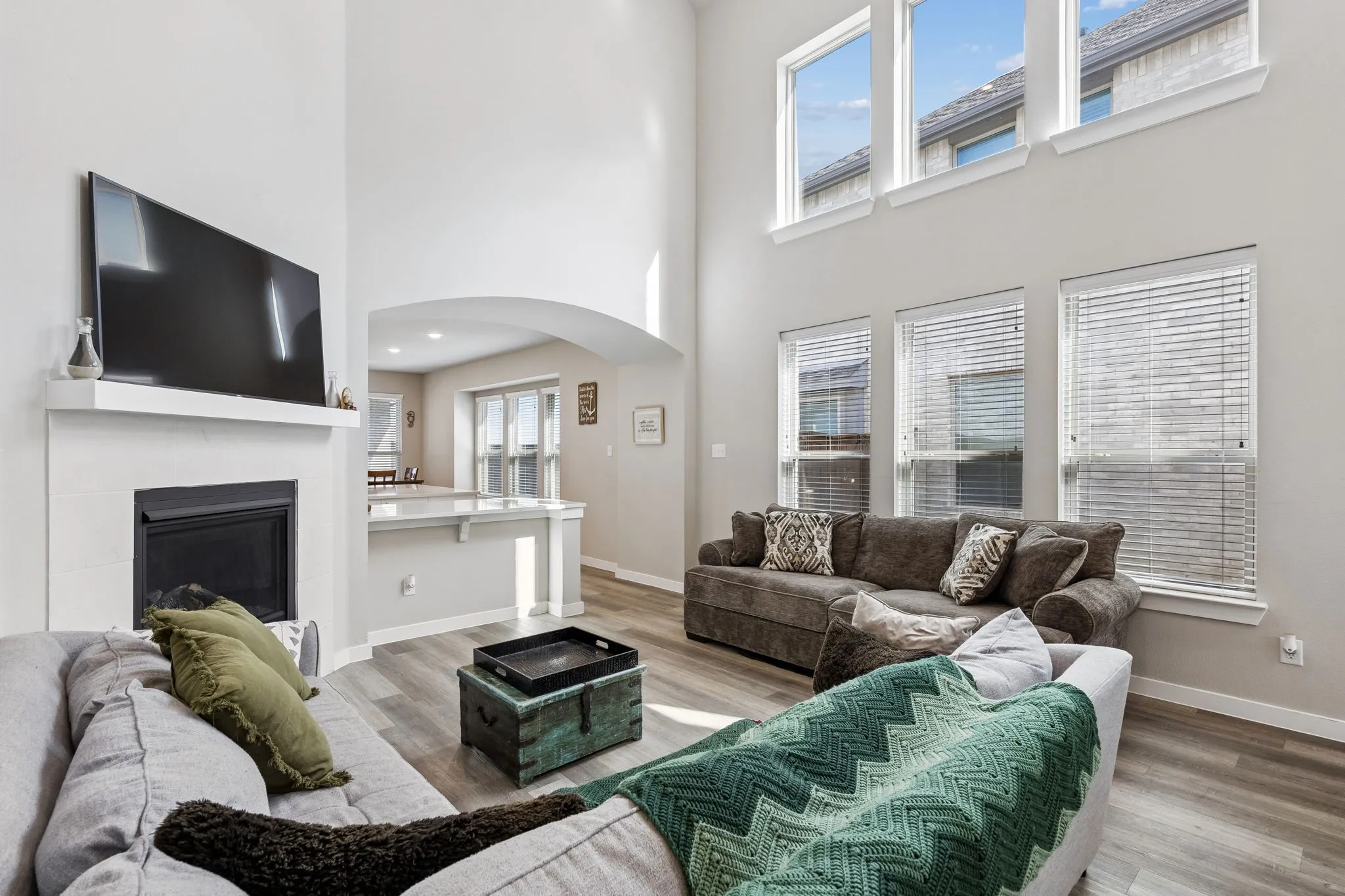 Vaulted ceiling, contemporary fireplace, wood-finish flooring, white mantel, and arched doorway