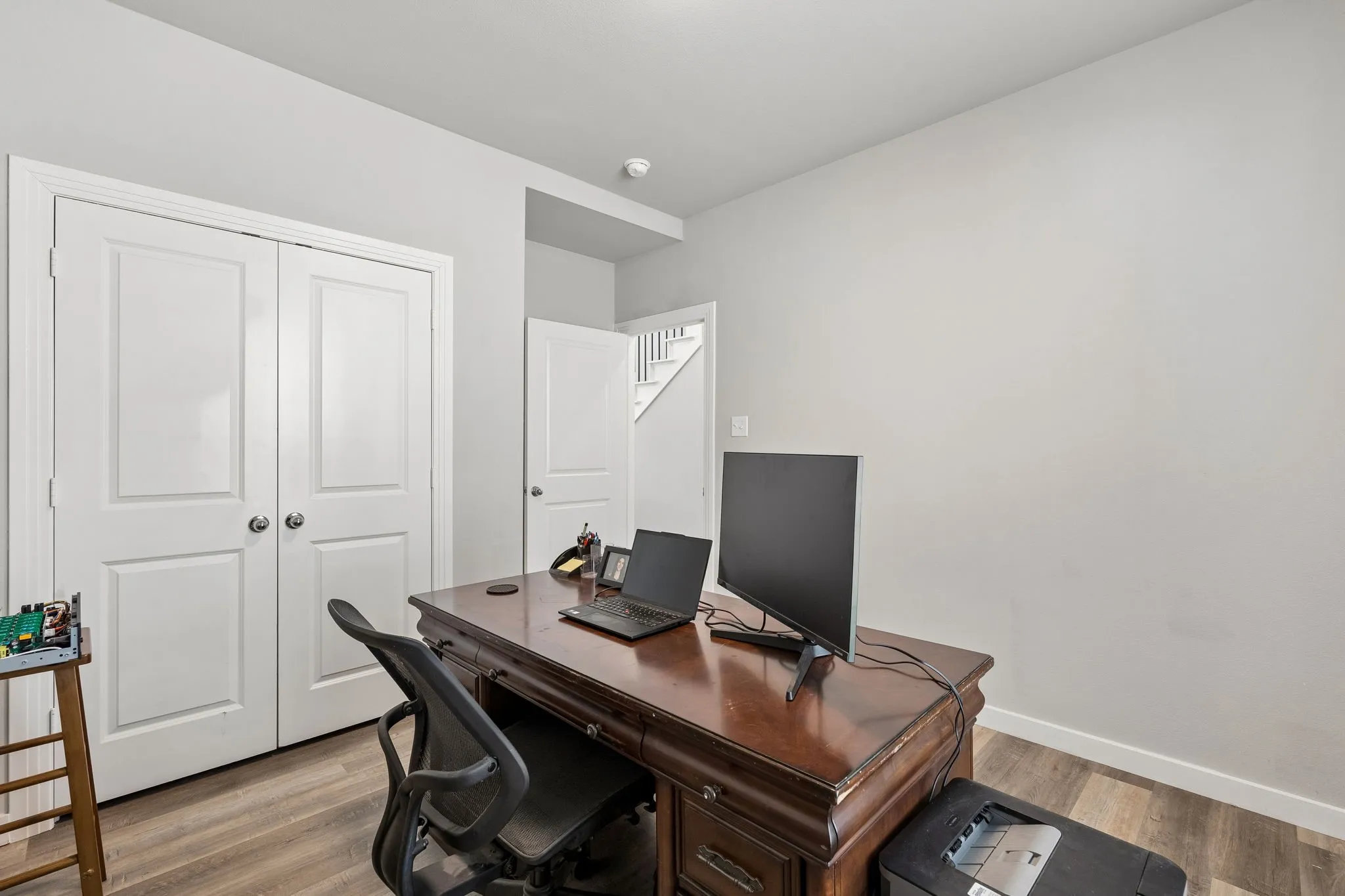 Light gray wall paint, wood-finish flooring, two-panel white bifold doors, and white trim
