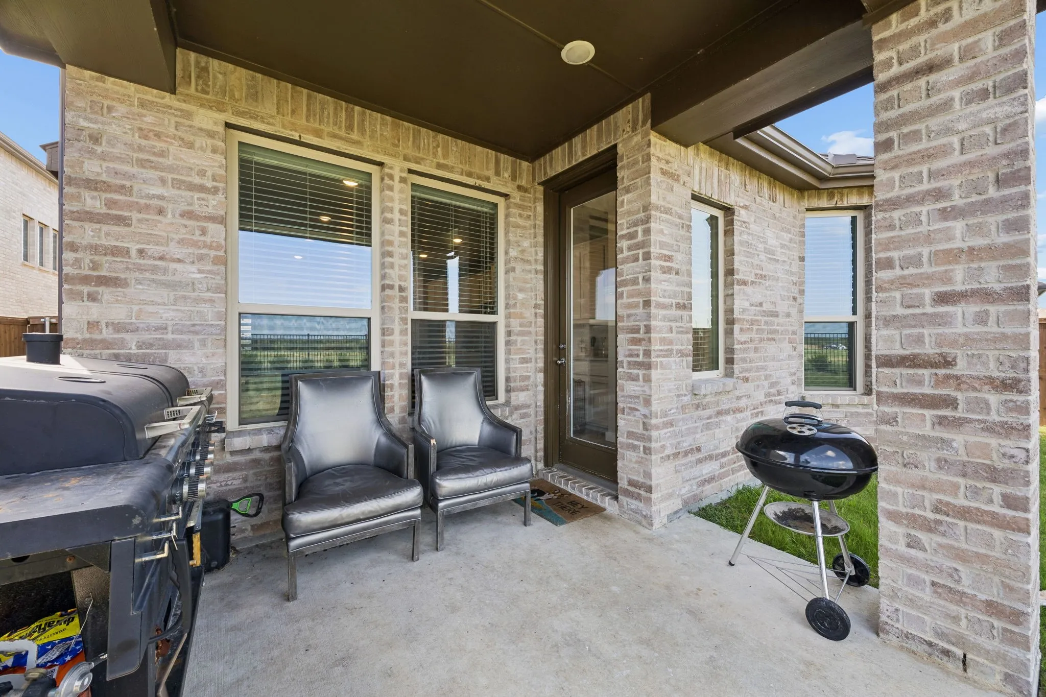 Covered patio featuring brick construction, concrete flooring, and multiple windows