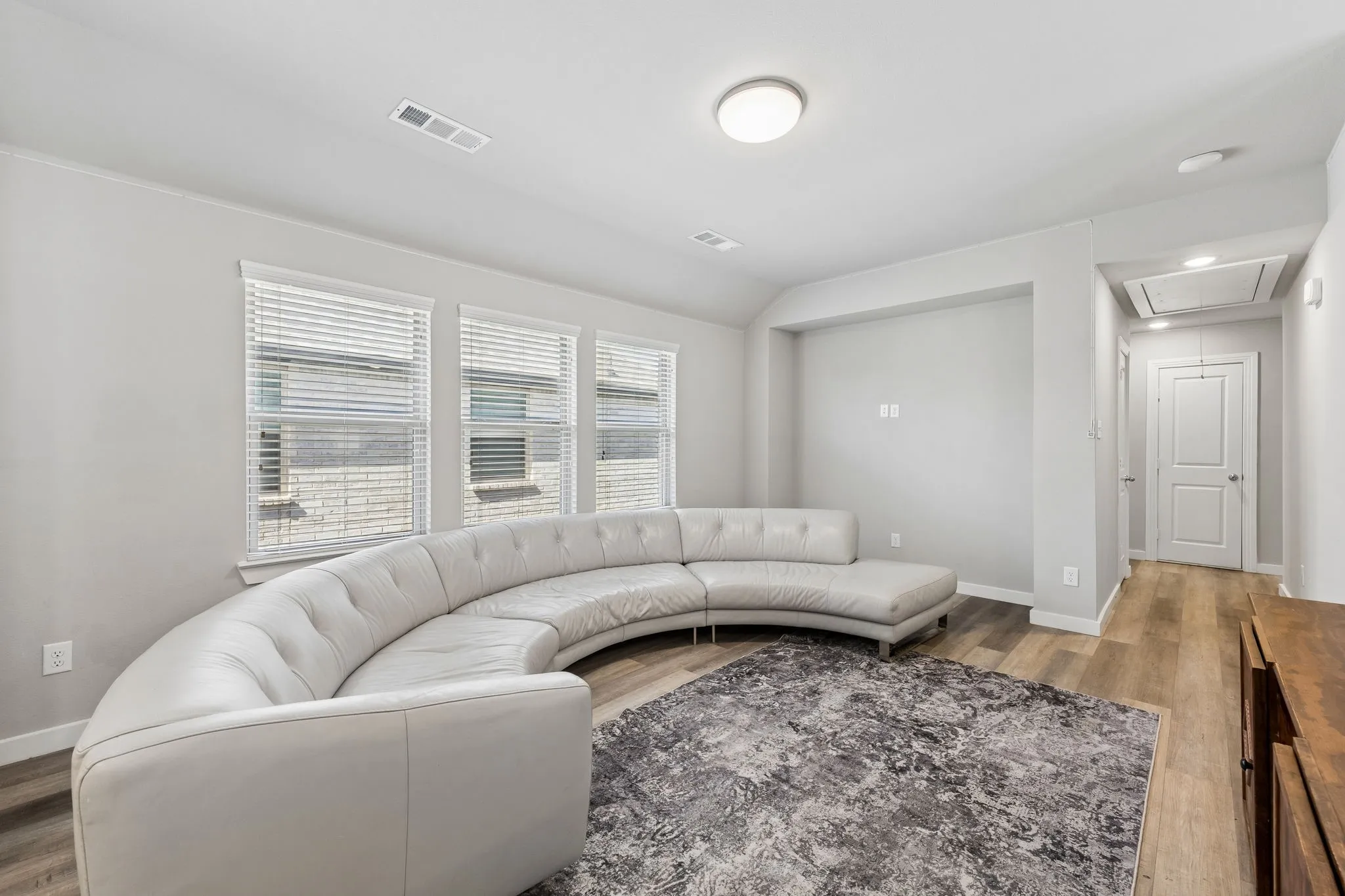 Recessed ceiling lighting, wood-finish flooring, and multiple windows with blinds