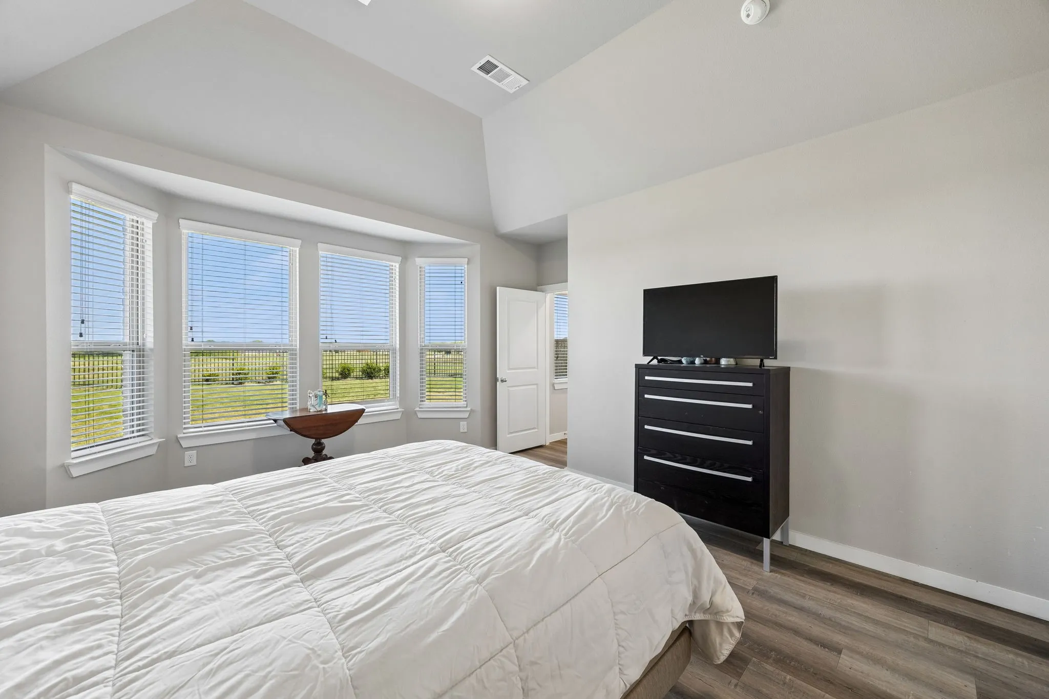 Bay window with multiple panels, vaulted ceiling, and wood-finish flooring