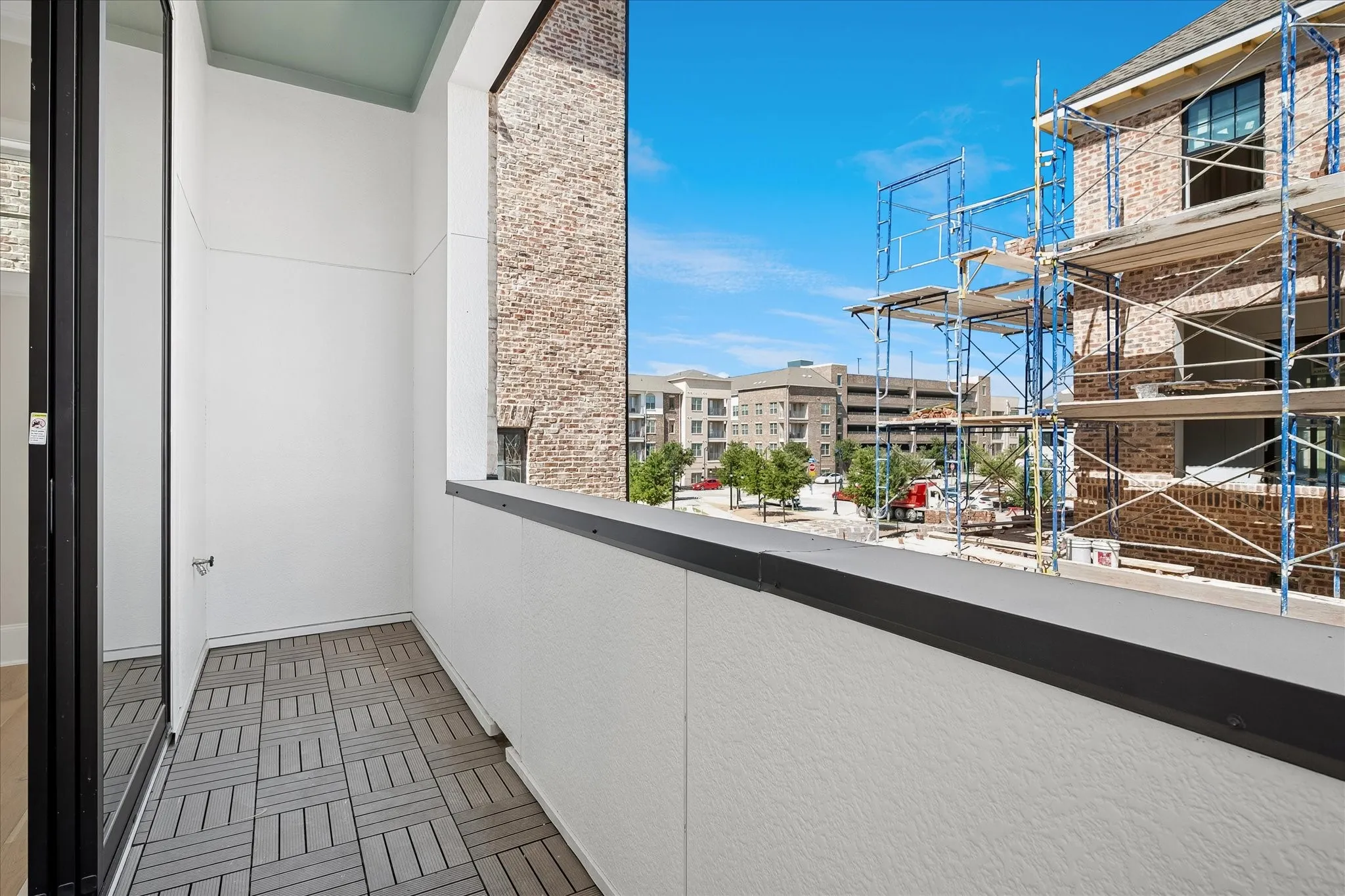 Balcony featuring wood-finish flooring, white stucco walls, and a black railing
