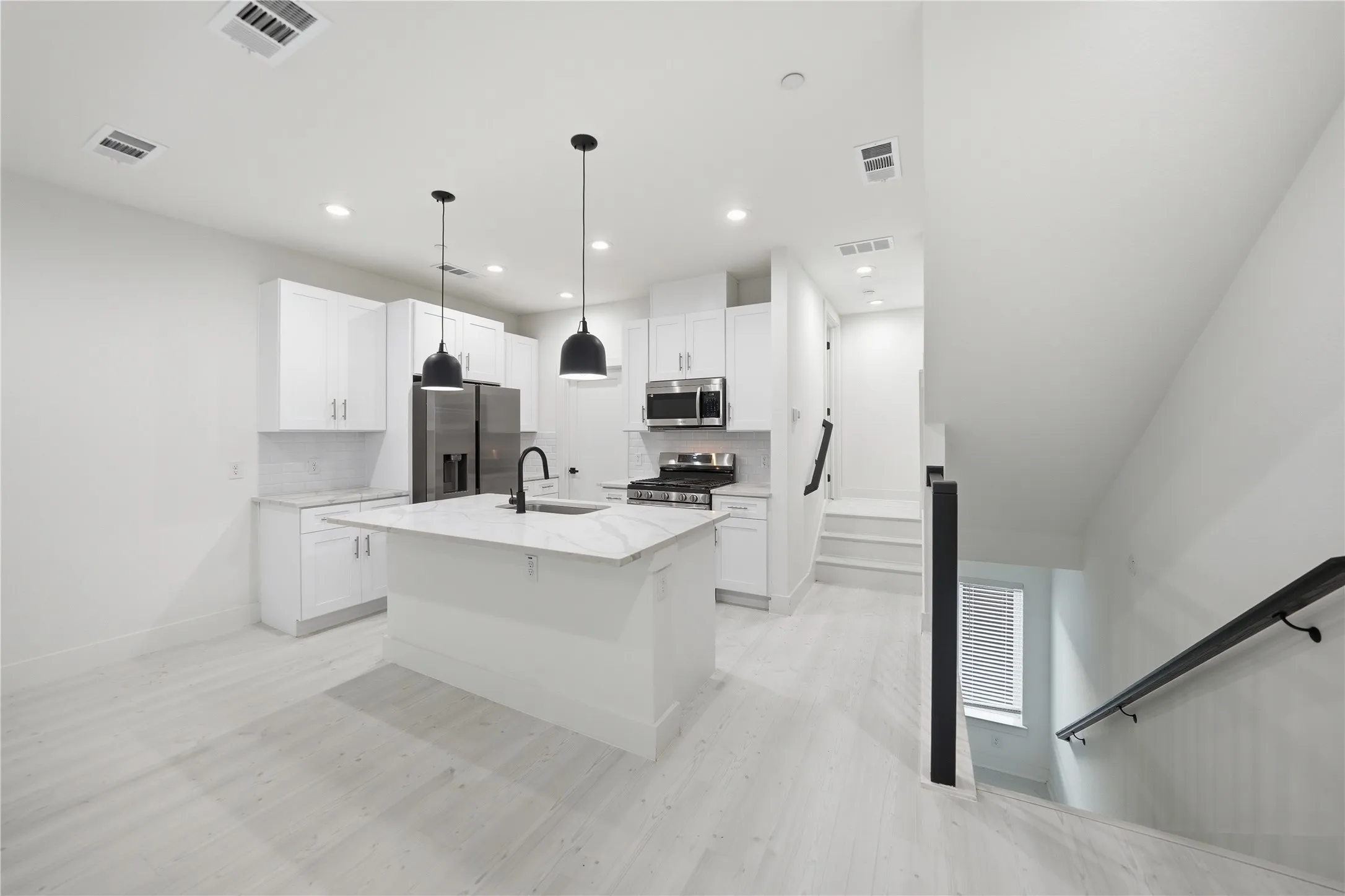 Modern kitchen featuring white cabinetry, a central island with a stone countertop, and stainless steel appliances