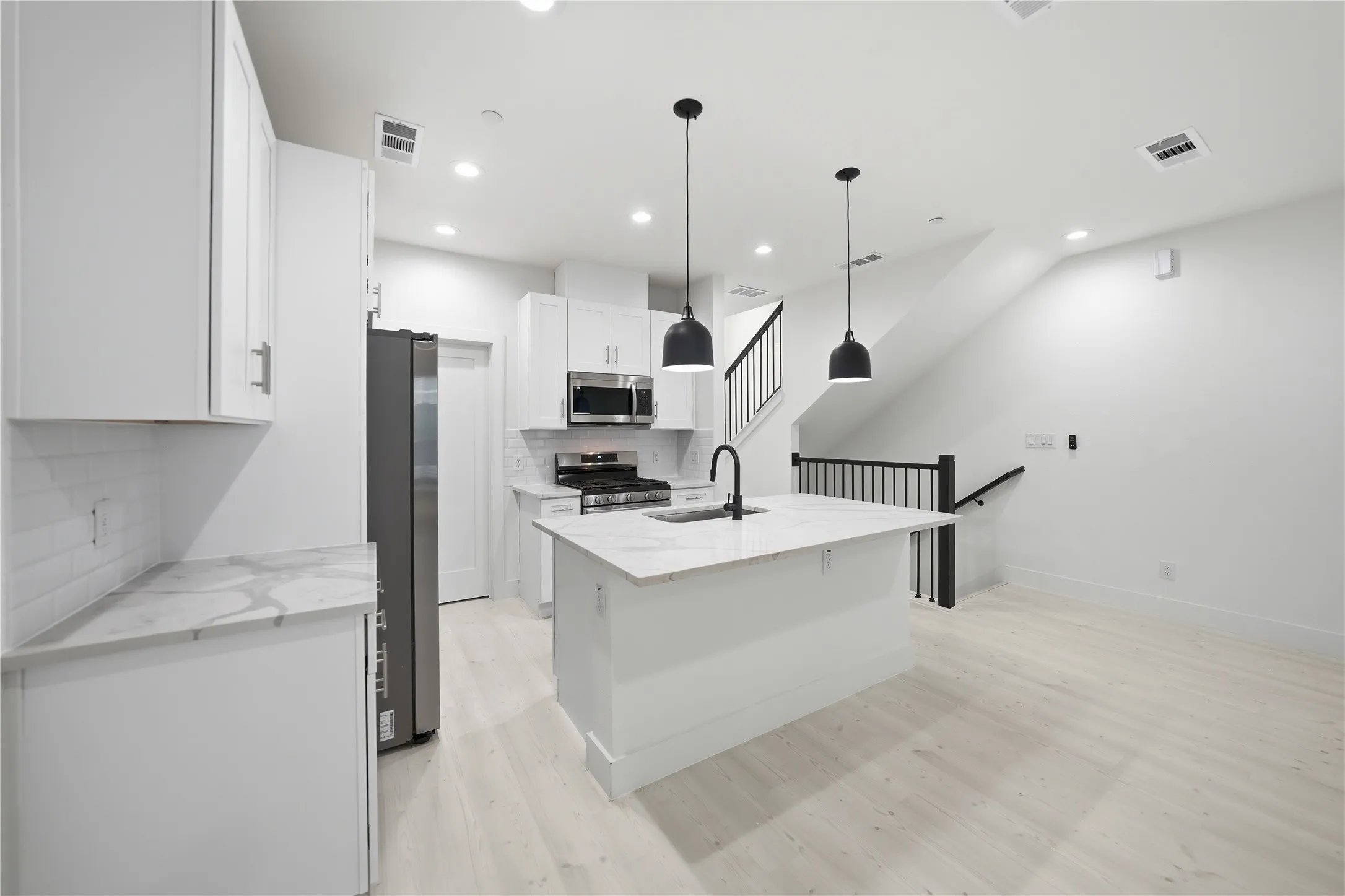 Modern kitchen featuring an island with a waterfall-edge countertop and matte black fixtures