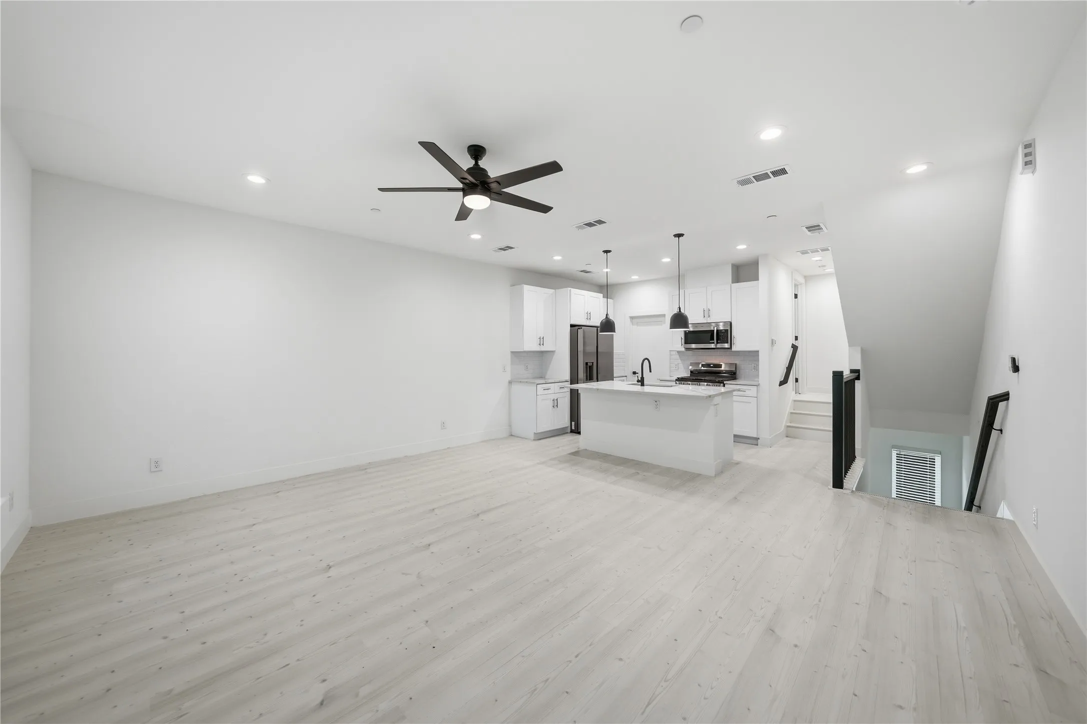 Open-concept living space featuring light wood-finish flooring, recessed lighting, and a modern ceiling fan