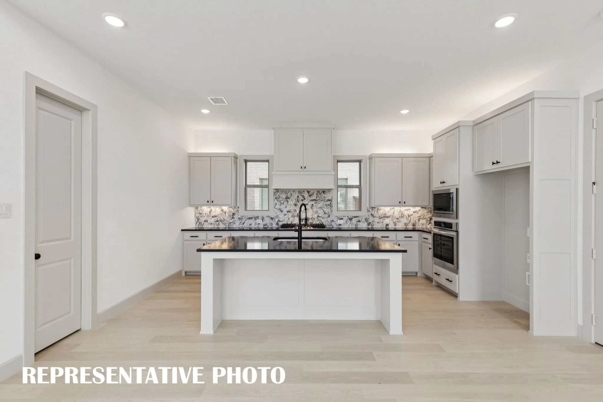 Beautiful flooring, outstanding cabinetry, striking countertops and modern stainless steel come together to form this dream kitchen!  REPRESENTATIVE PHOTO