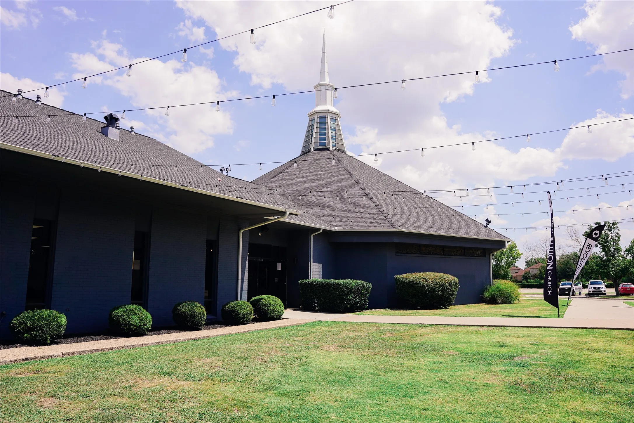 Structure featuring a central steeple, dark roofing, and dark exterior siding